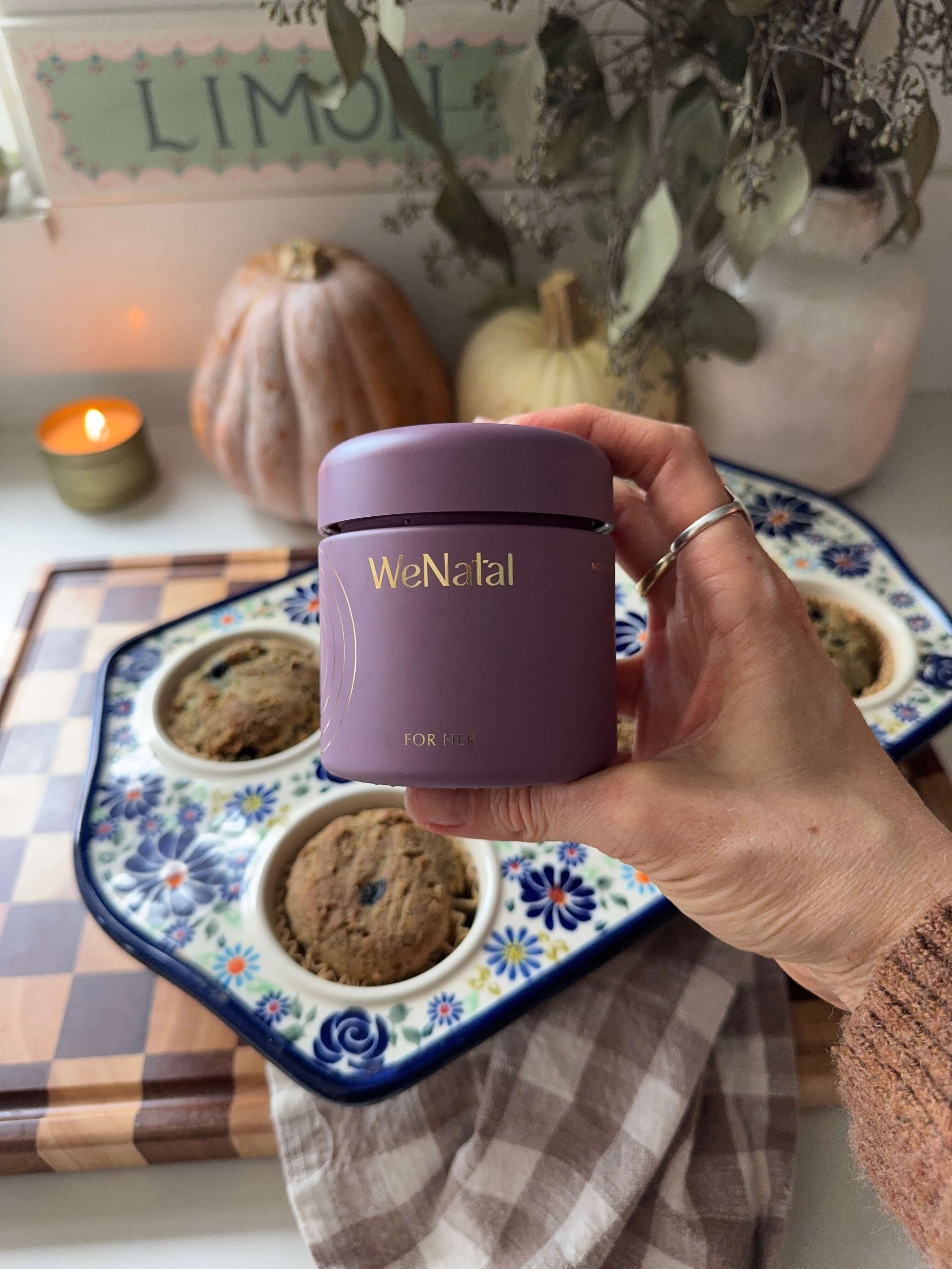 hand holding wenatal supplements infant of muffins in muffin pan by candle light in kitchen