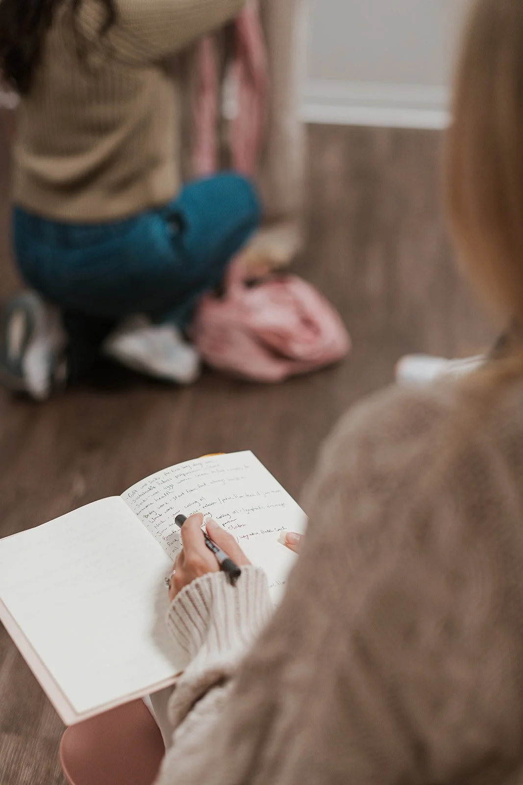 Woman taking notes in notebook for The Postpartum Course by Megan Limon.