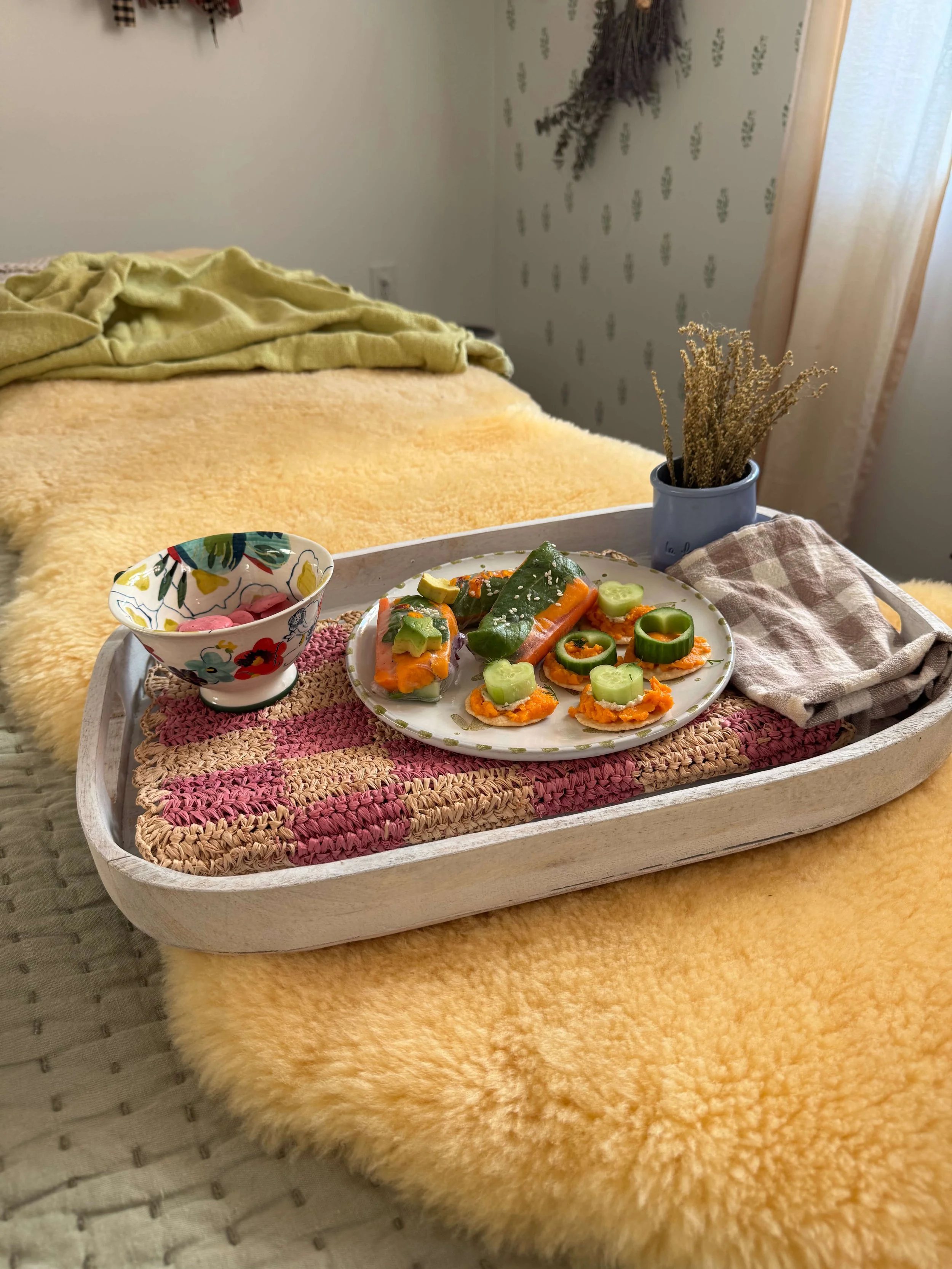 snacks on bedside tray on bed with dried florals and veggies on plate and postpartum snacks