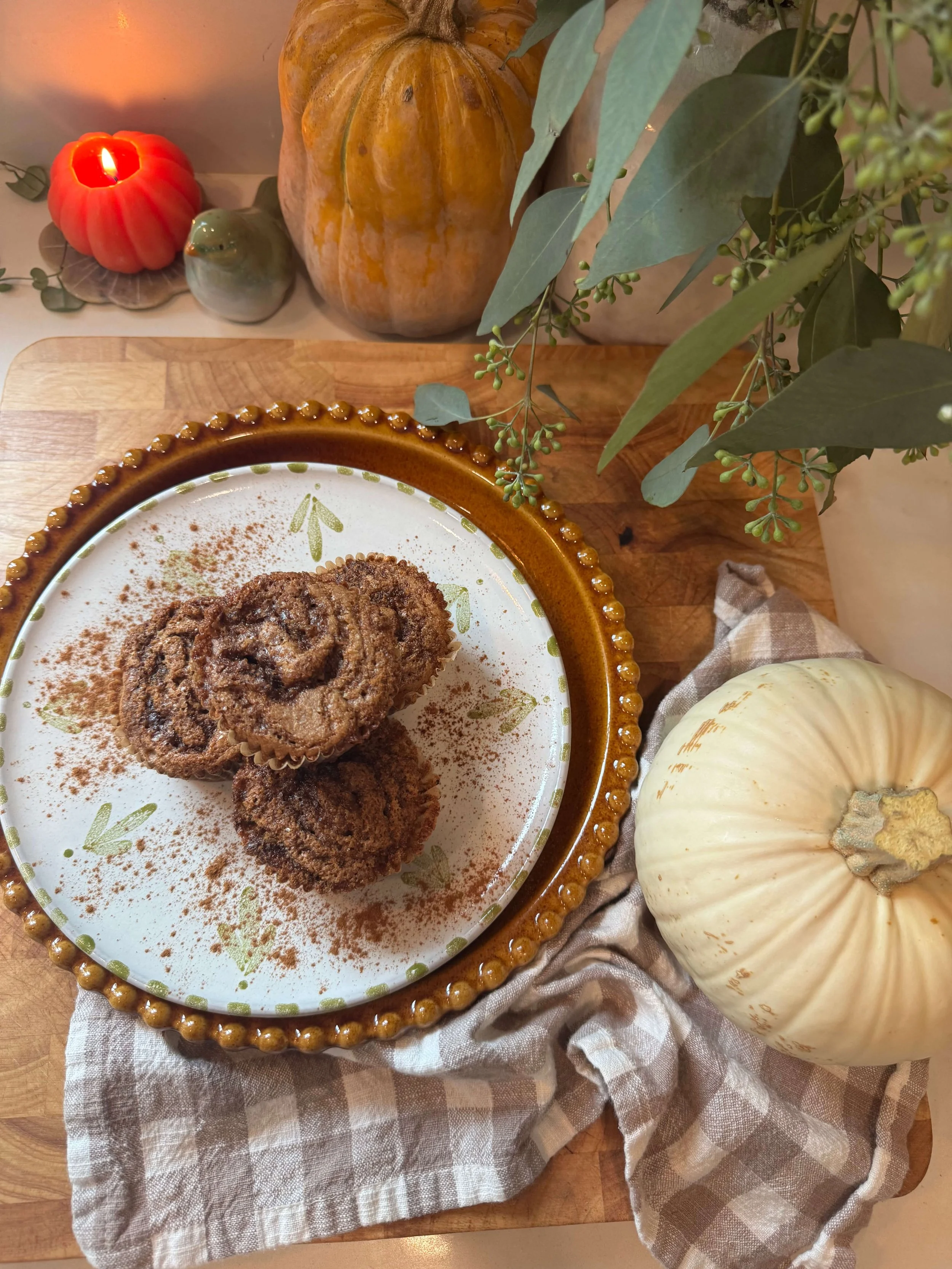 postpartum cinnamon swirl muffins on plate in kitchen with pumpkin