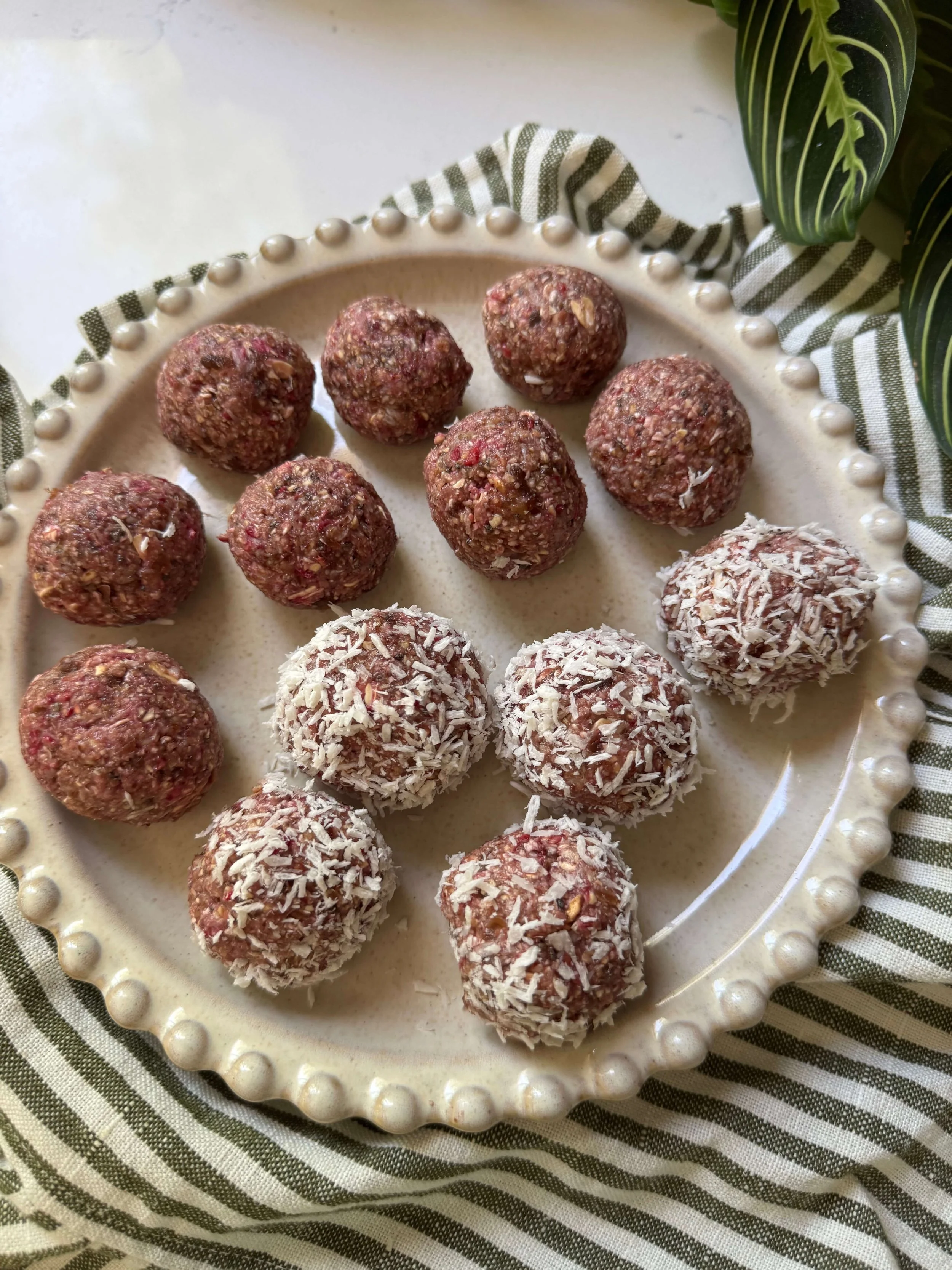 raspberry oat balls on plate in kitchen with plant