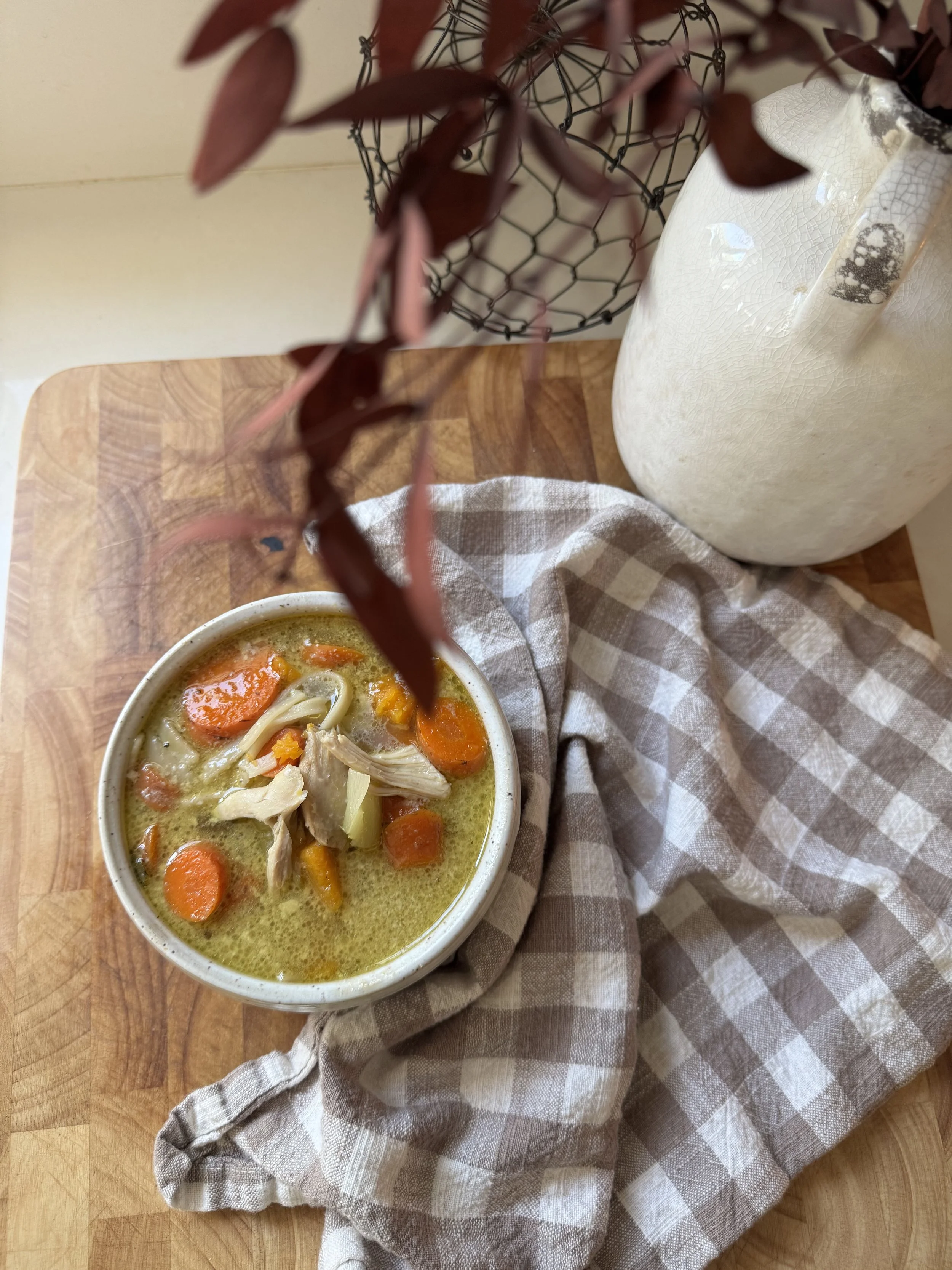 soup bowl on counter by autumn florals carrots chicken on gingham napkin