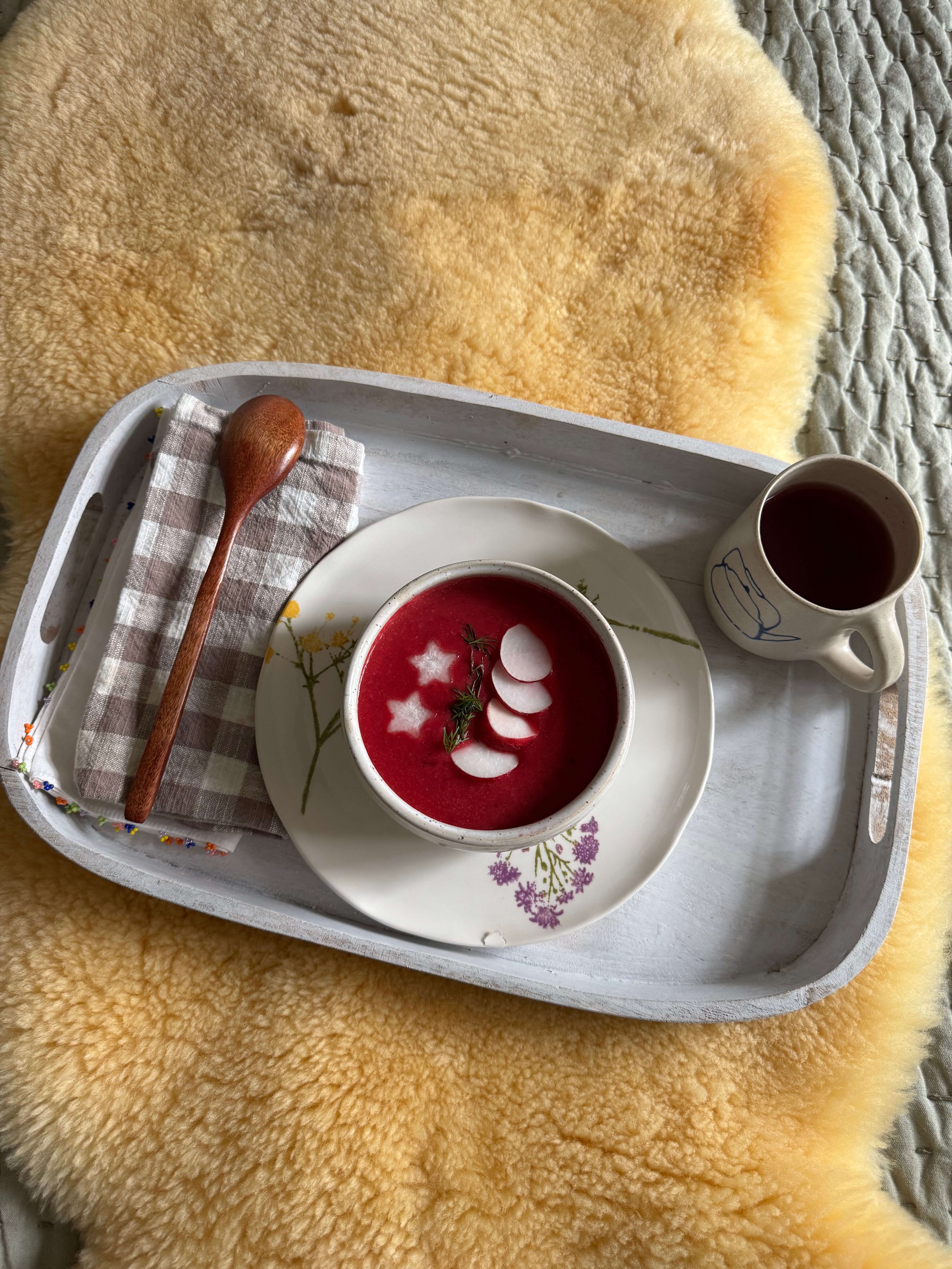 beet soup in bowl on bedside tray on the bed sheepskin