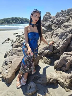 Model wearing DONBERNAE tropical sarong dress on a coastal island beach