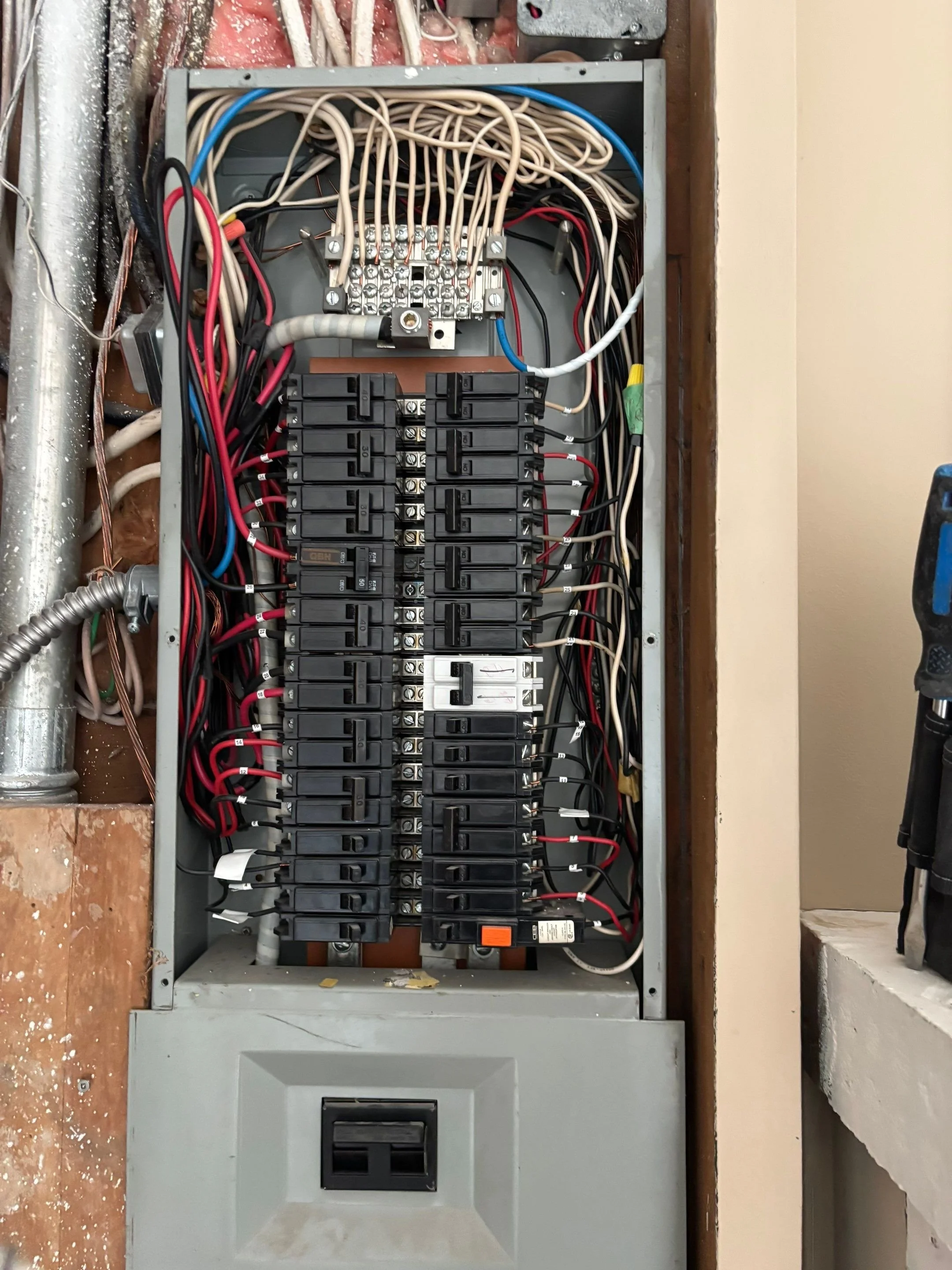 Aging fuse box being replaced with a modern breaker panel