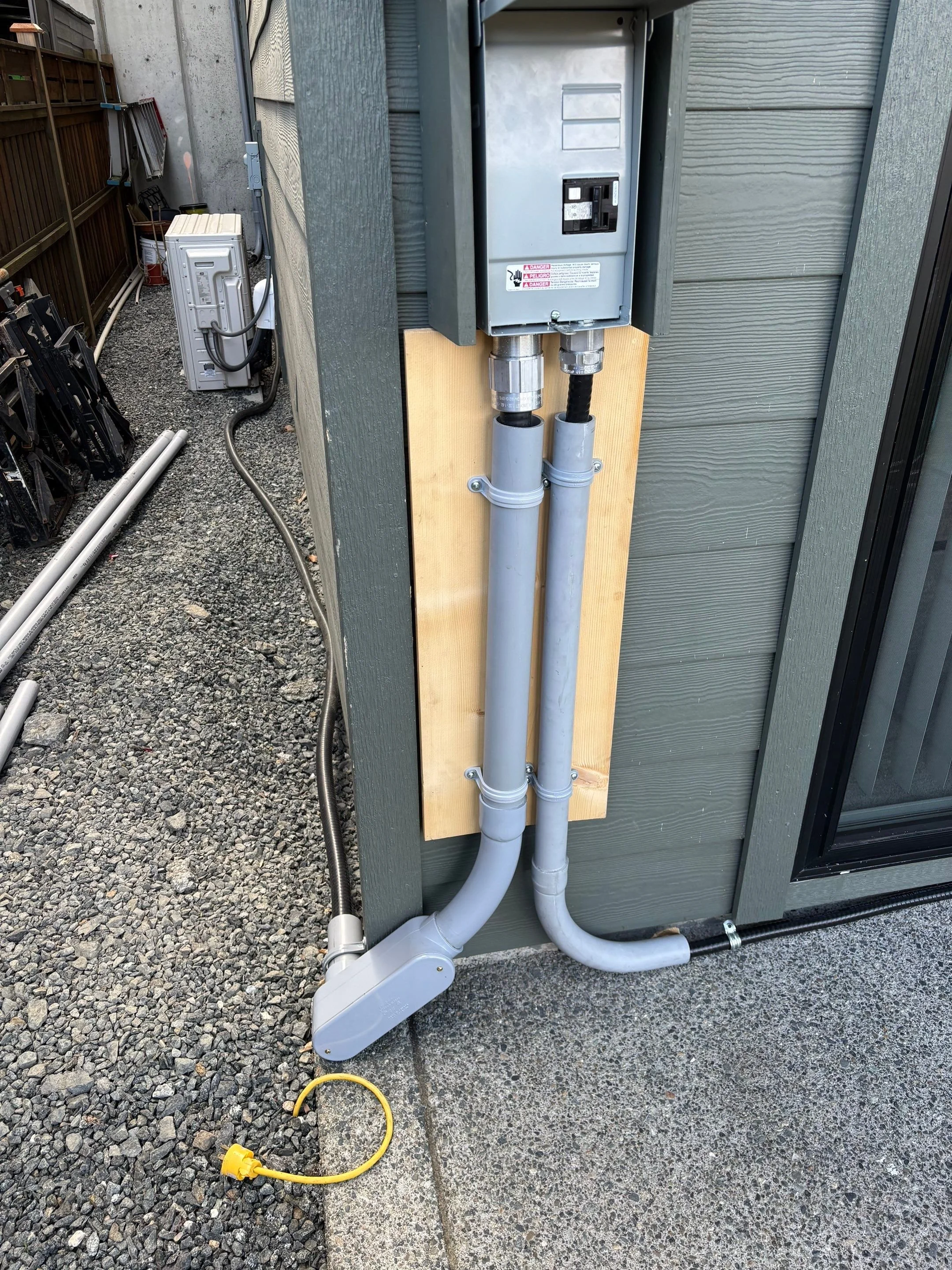 Exterior hot tub disconnect with PVC-protected conduit runs feeding the spa in Langford