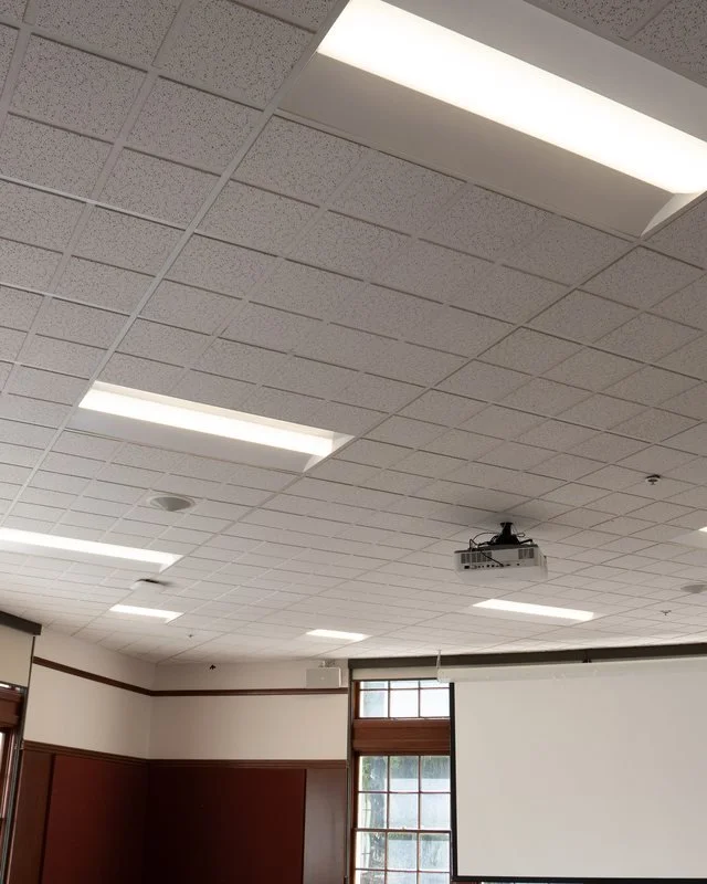Grifflyn Electric technician verifying a ceiling smoke detector next to a fire alarm