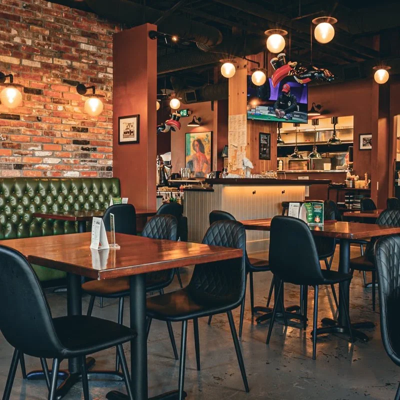 Brick feature wall with globe sconces and pendant lighting in the Saxe Point Public House dining room in Esquimalt