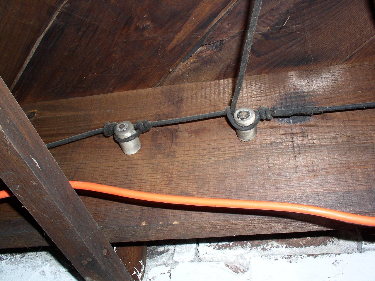 Aging knob and tube wiring buried in attic insulation, a recognized fire hazard