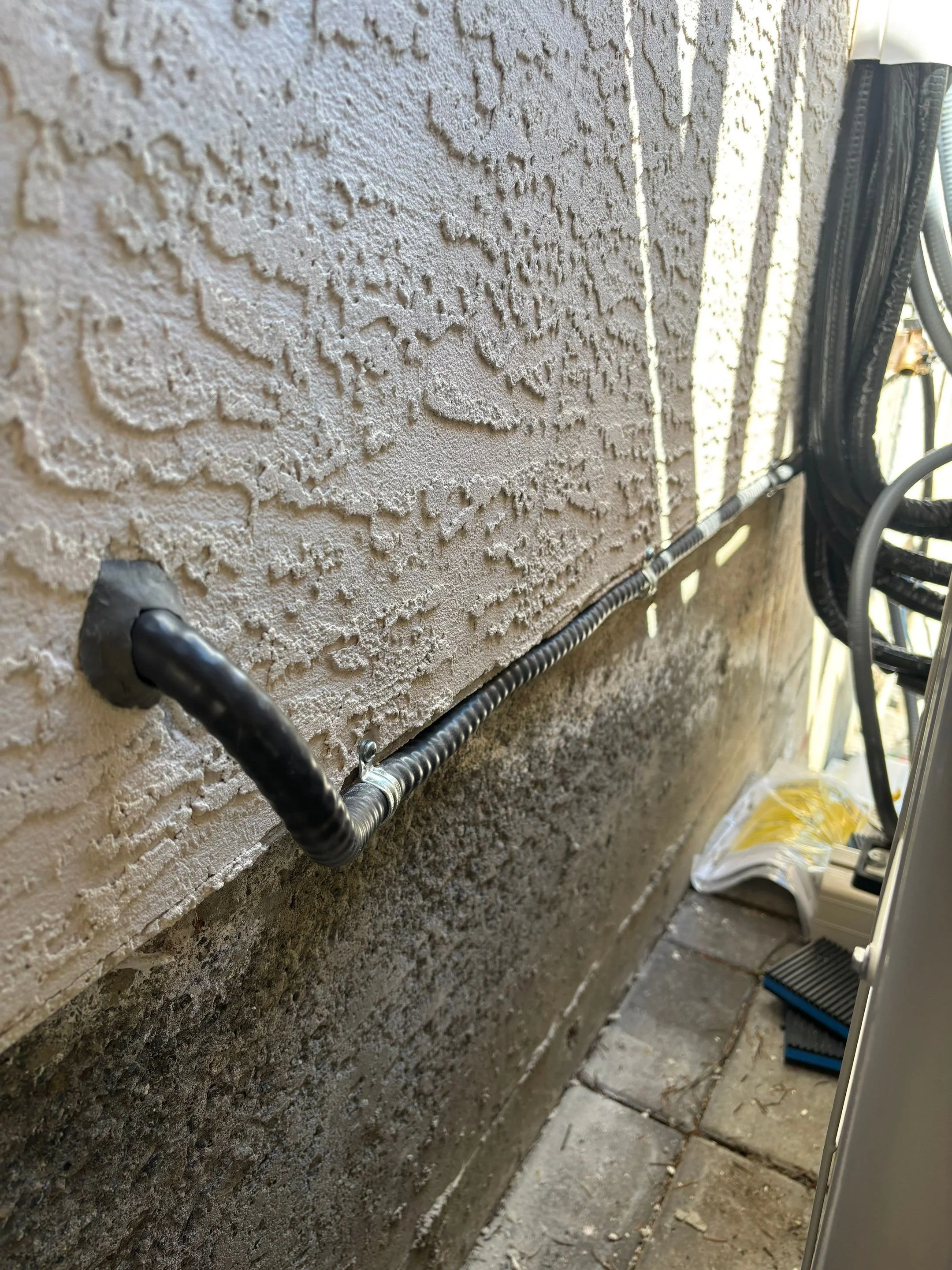 Heat pump cable sealed where it penetrates the exterior stucco wall of a Victoria home