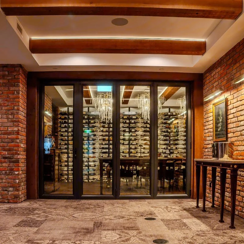Wine cellar with cove lighting, crystal chandeliers and illuminated stone bottle display