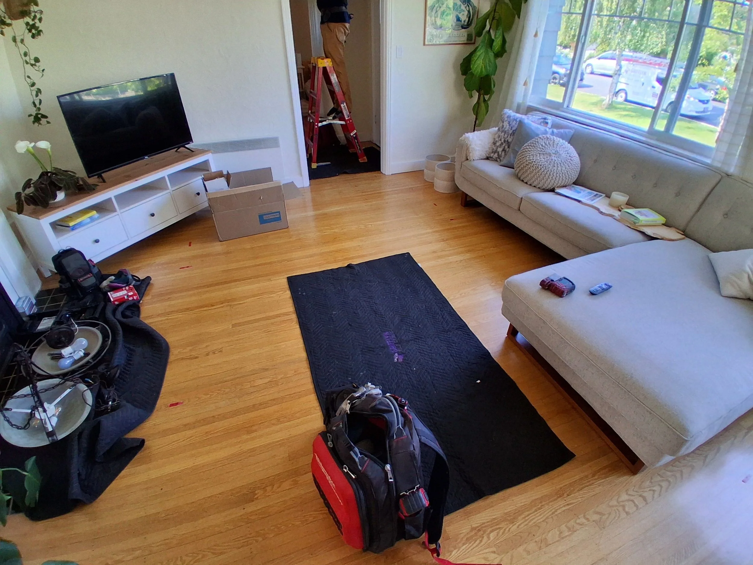 Grifflyn Electric drop cloths and tools laid out during a recessed lighting install with a ladder in the hallway