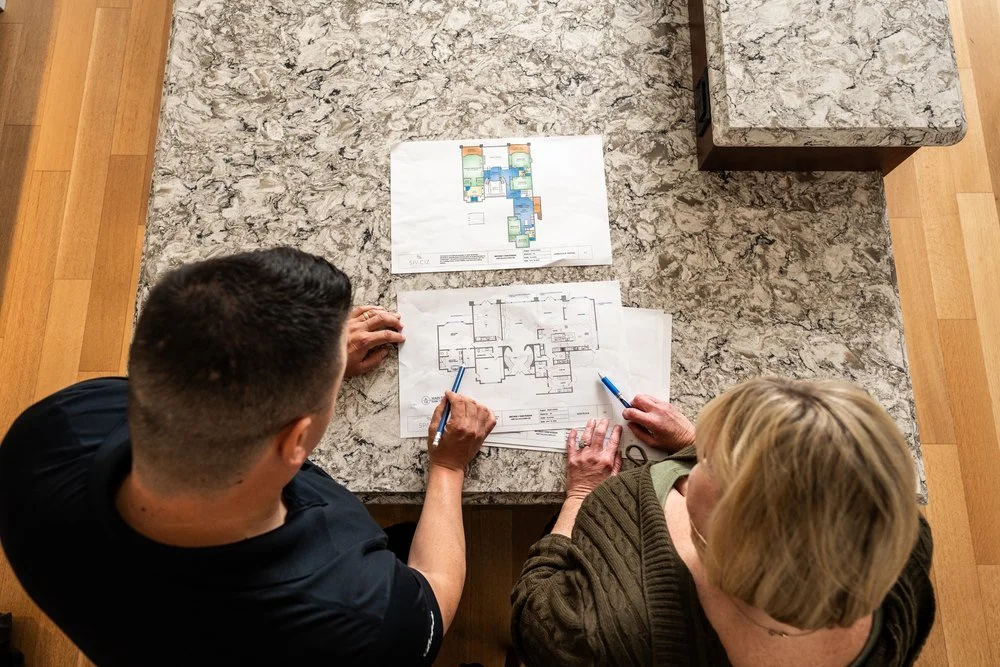 Grifflyn electrician and a homeowner reviewing renovation floor plans at a kitchen island