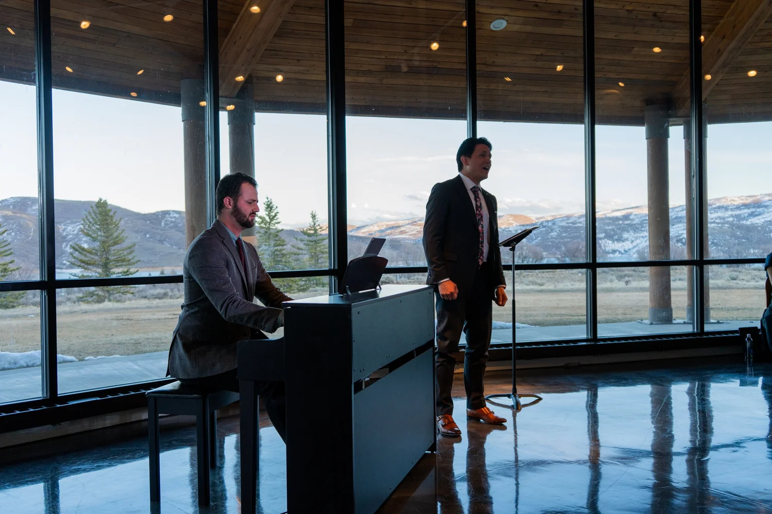 A Park City Opera singer and pianist performing in front of windows overlooking the Wasatch Back