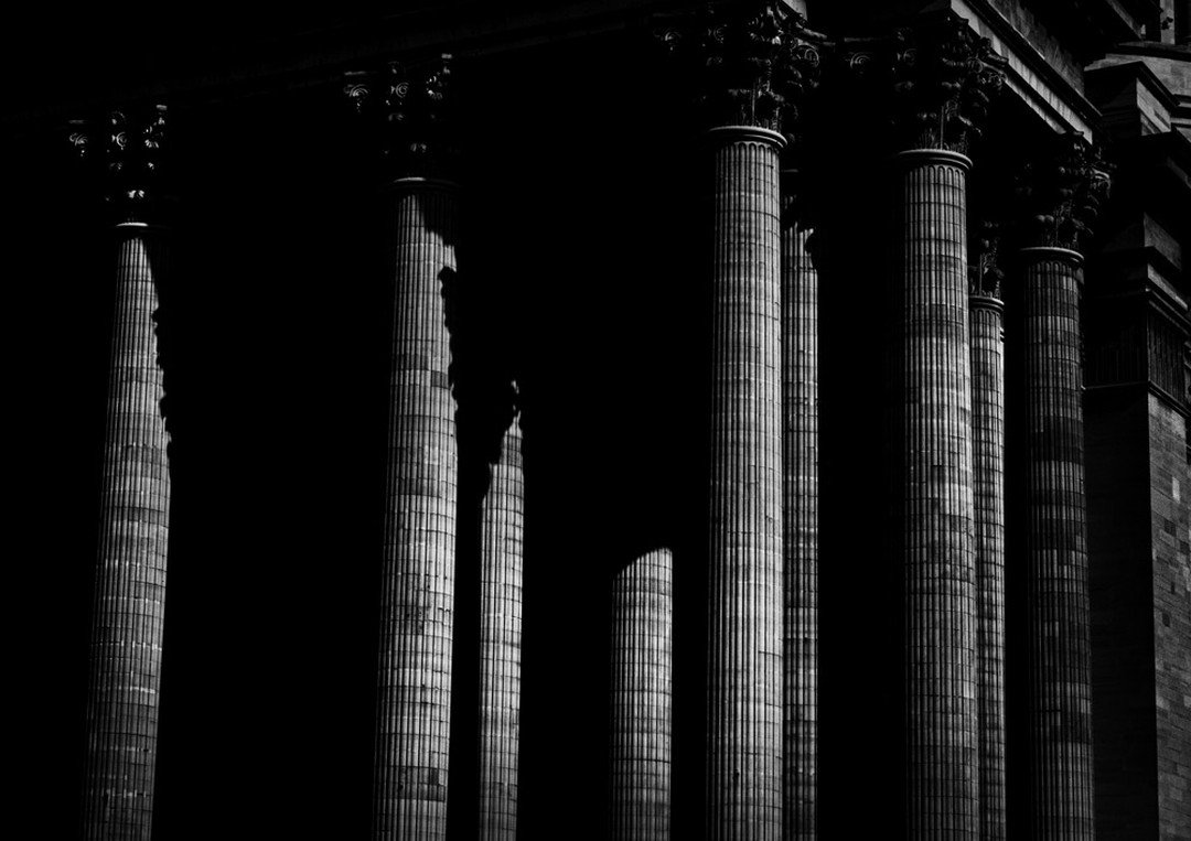 Black and white image of classical architectural columns with ornate capitals