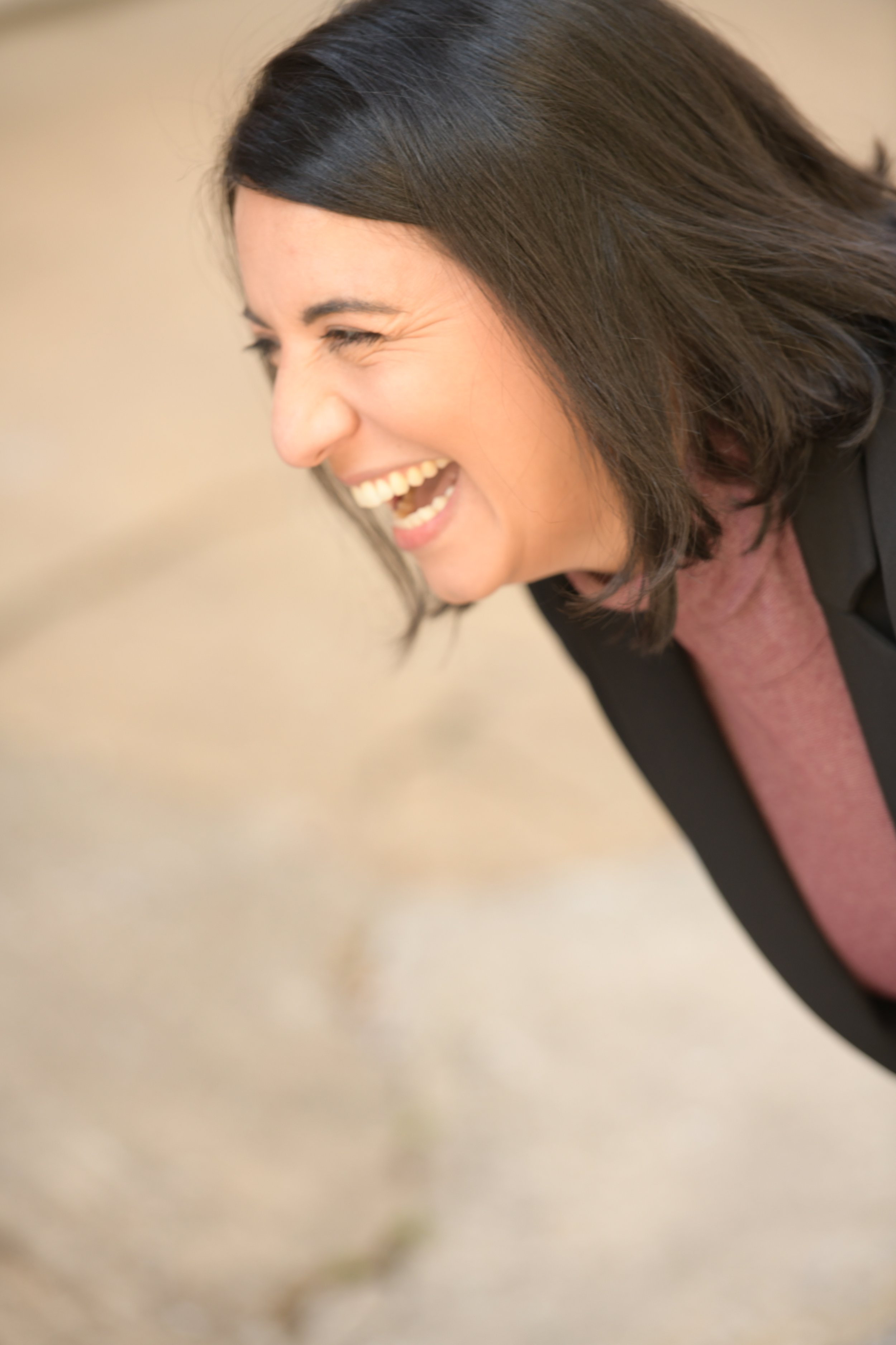 A woman with dark brown hair laughing or smiling with her eyes closed.