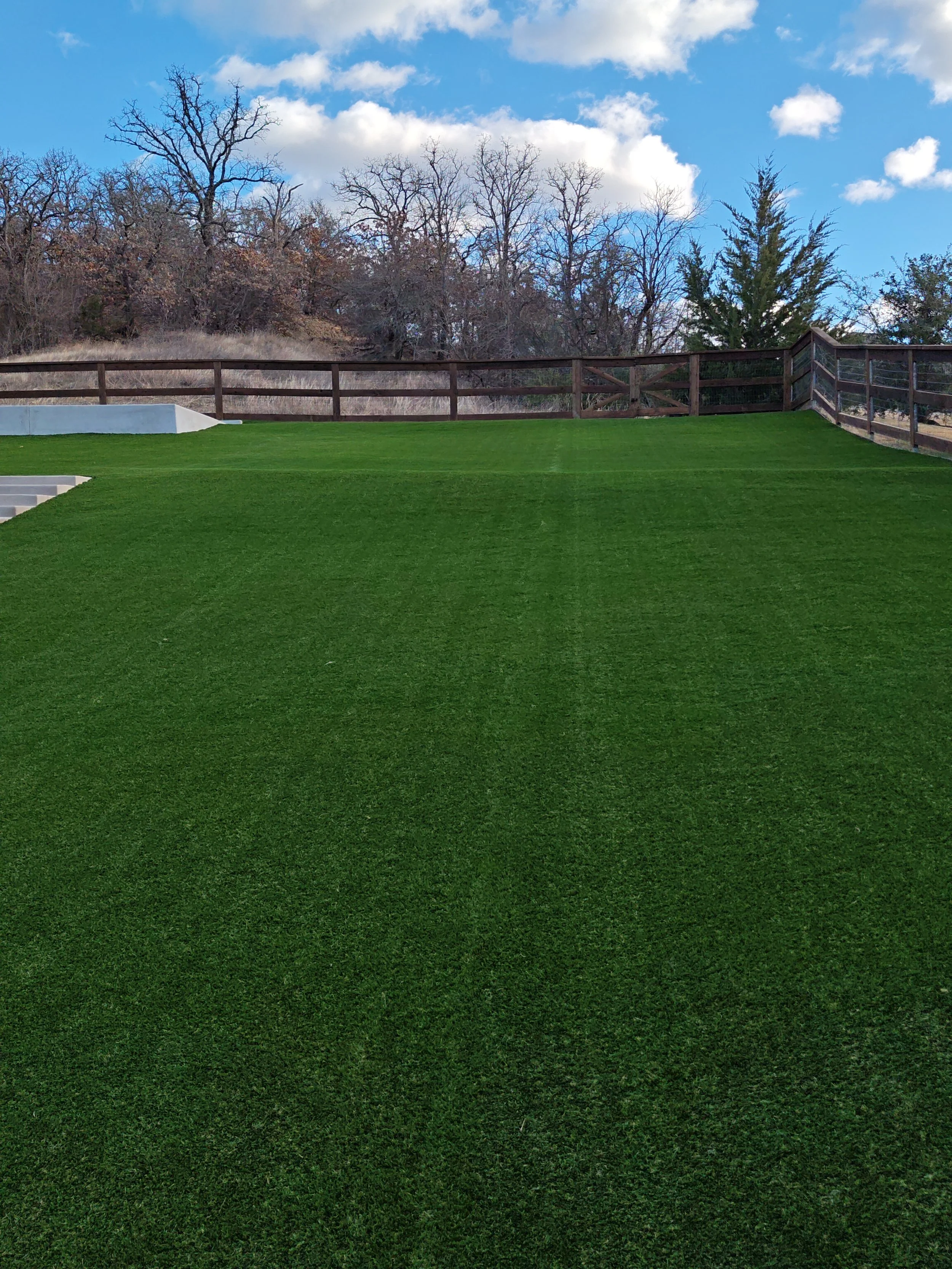 Large residential backyard with professional artificial turf installation in Dallas-Fort Worth, showcasing a flat, low-maintenance synthetic lawn.