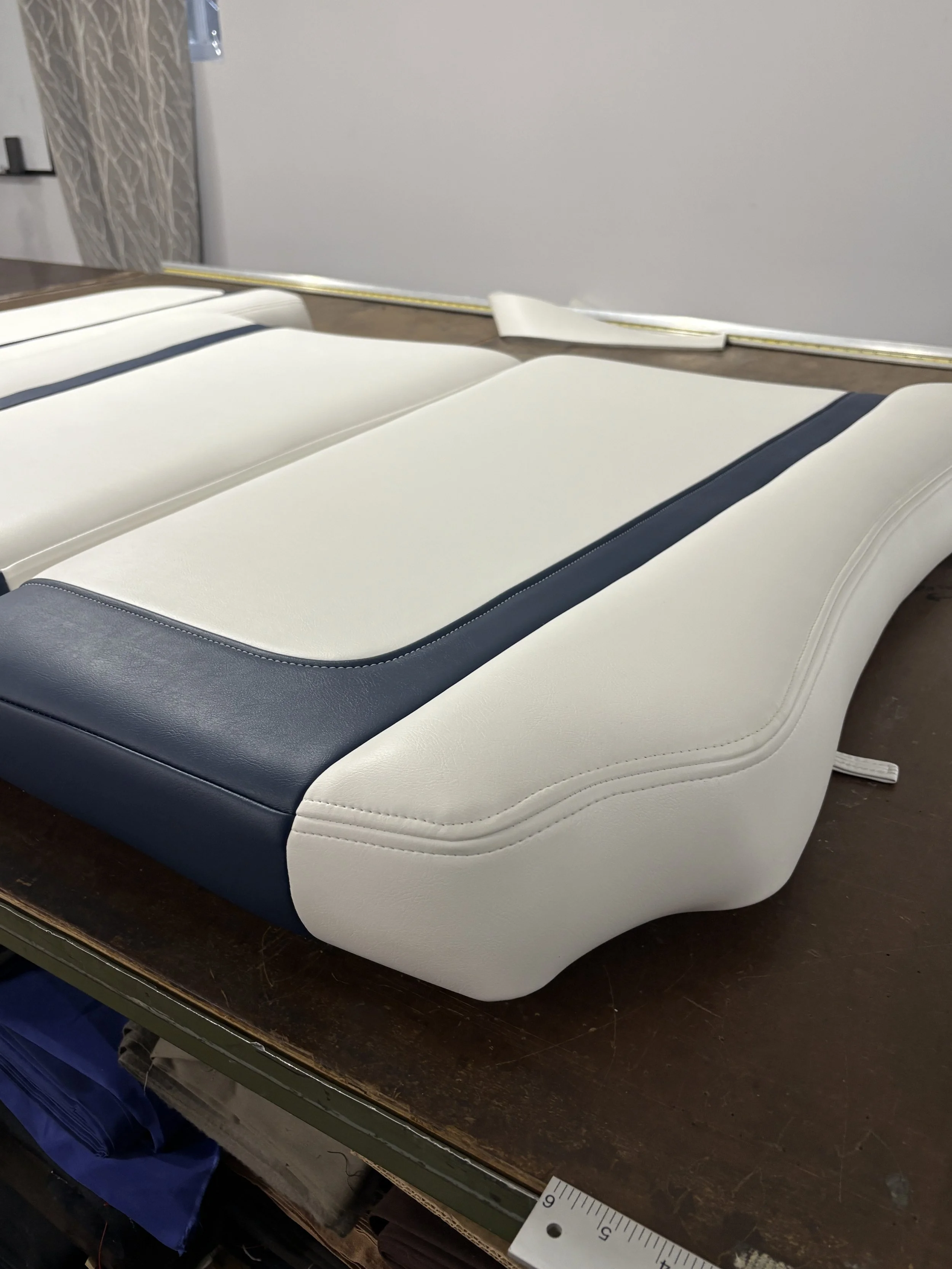 A medical or dental examination table with a padded surface in with white and dark blue sections, placed on a dark wooden table.