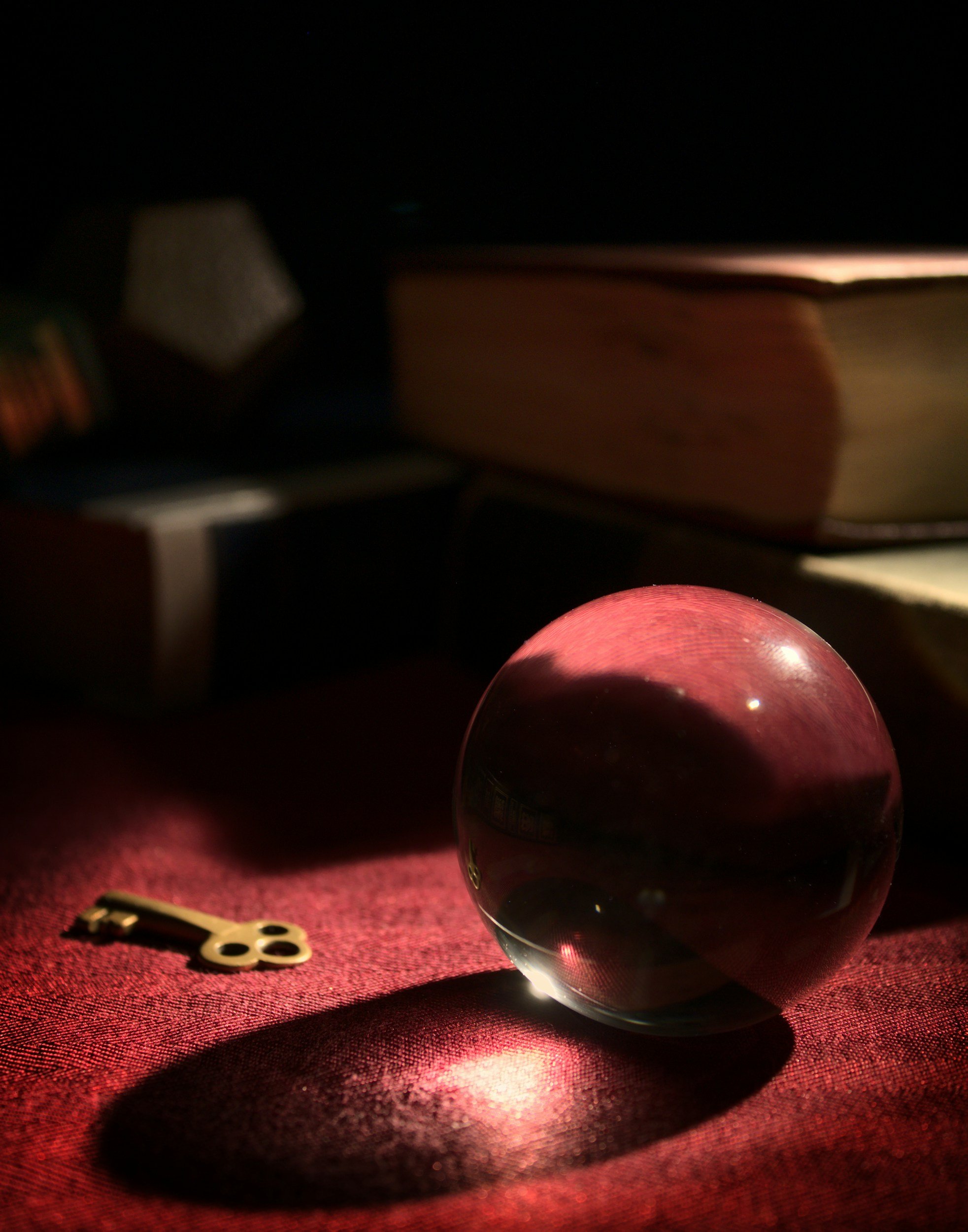 Close up of a crystal ball and a small brass key on a fabric topped table