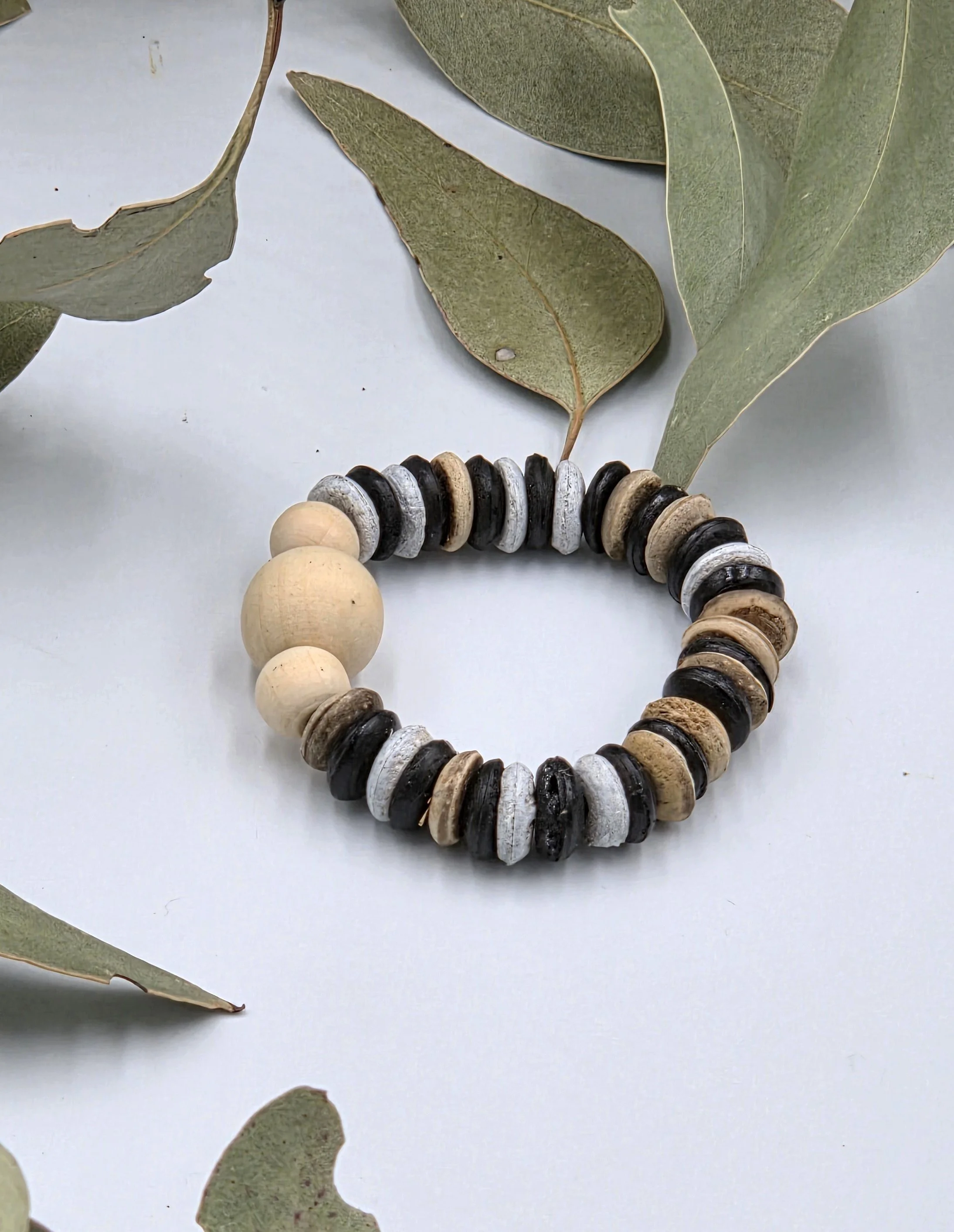 Striped brown and white coconut disc elastic bracelet featuring raw natural wood beads as a central focal point