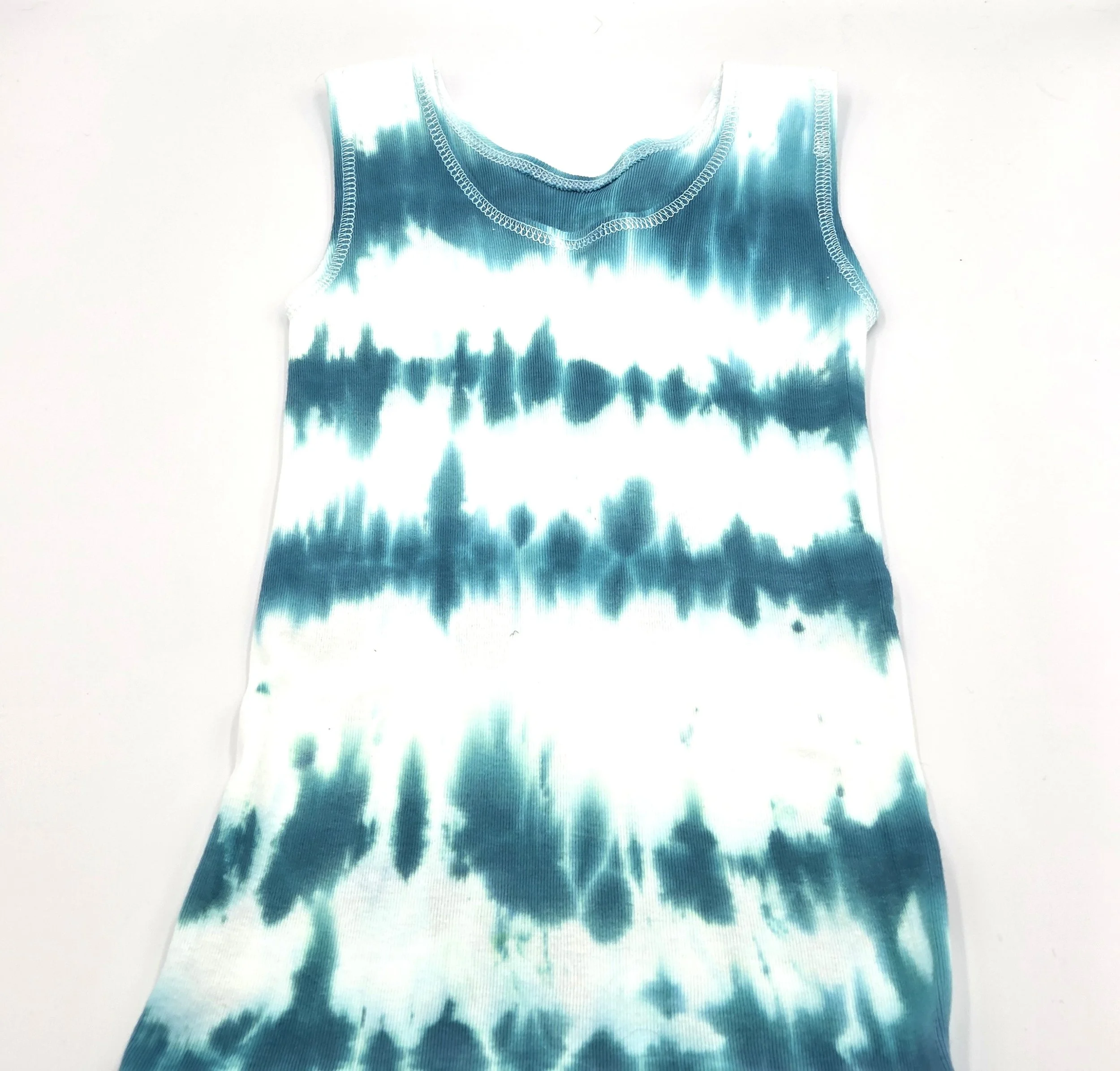 back view of child's white singlet displaying a vertical tie-dye pattern of deep sea green wave lines.