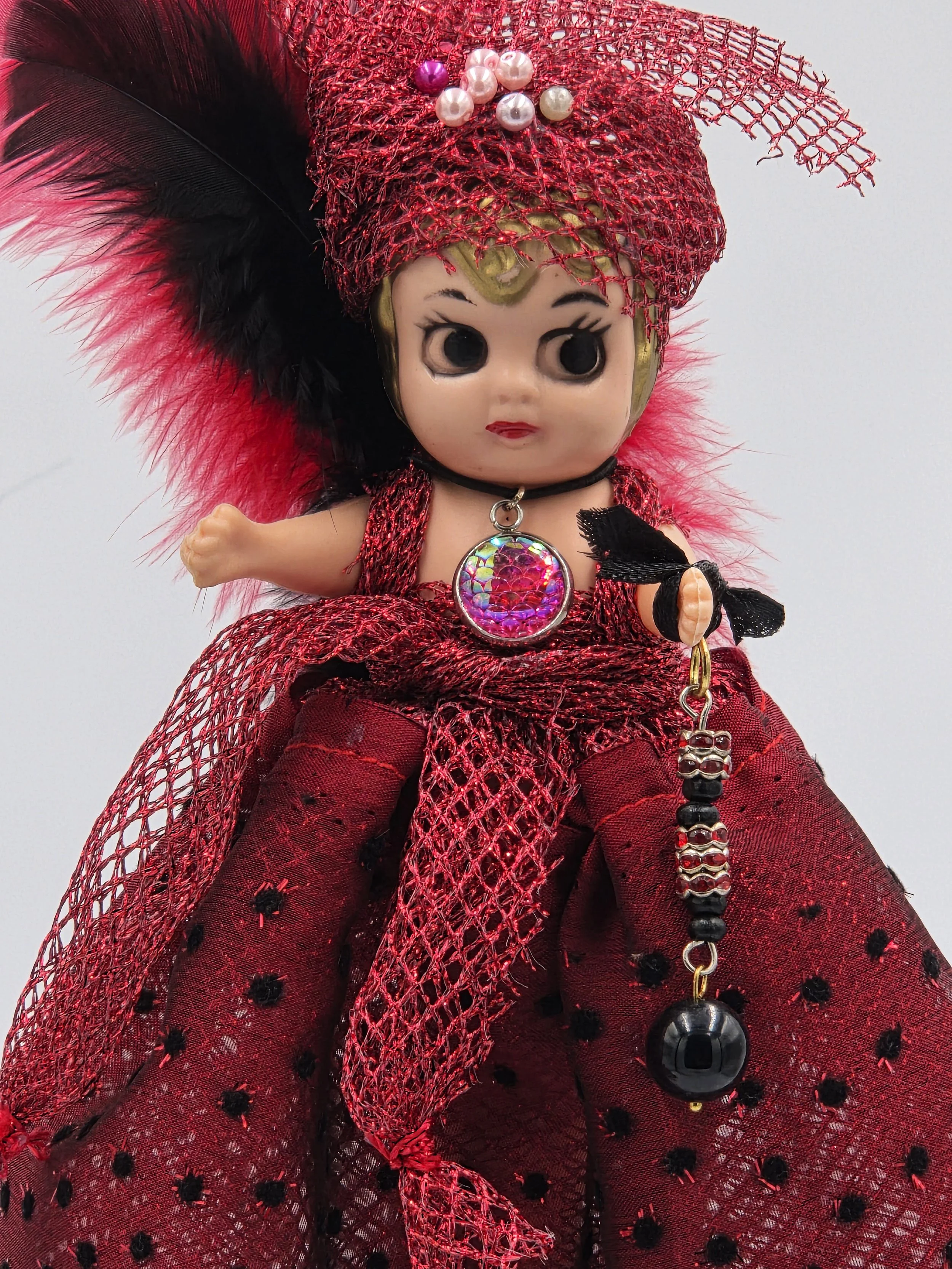 close up of Carmen Figure: OOAK 30cm art doll in striking red and black shiny netting with a feather and pearl headdress.
