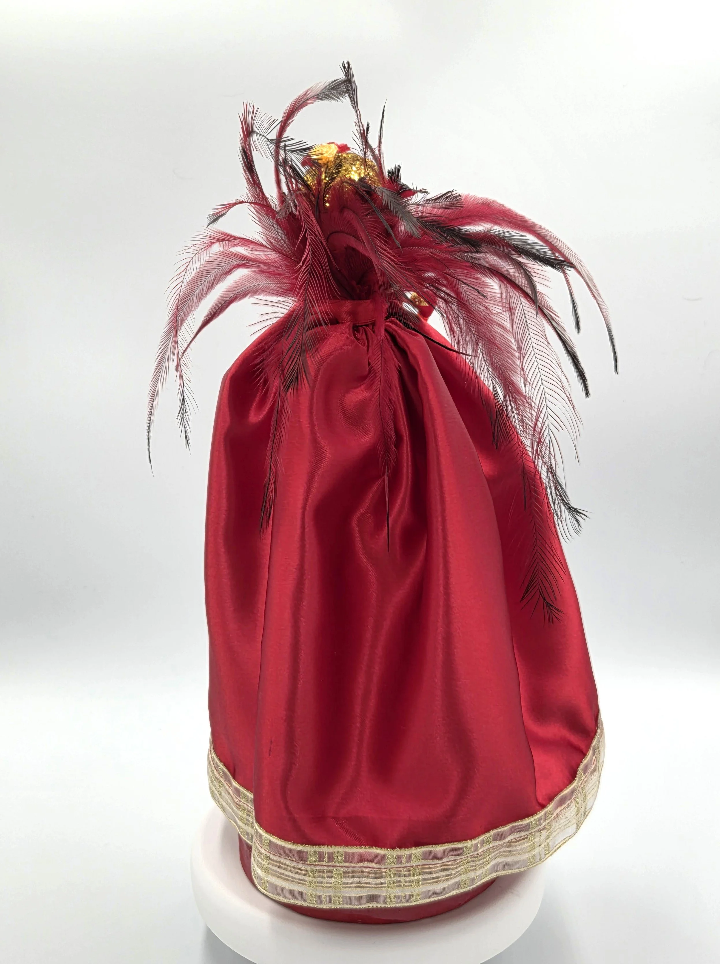 Rear view OOAK 33cm red satin art doll with a dramatic red and black feather backdrop on a red wooden stand.