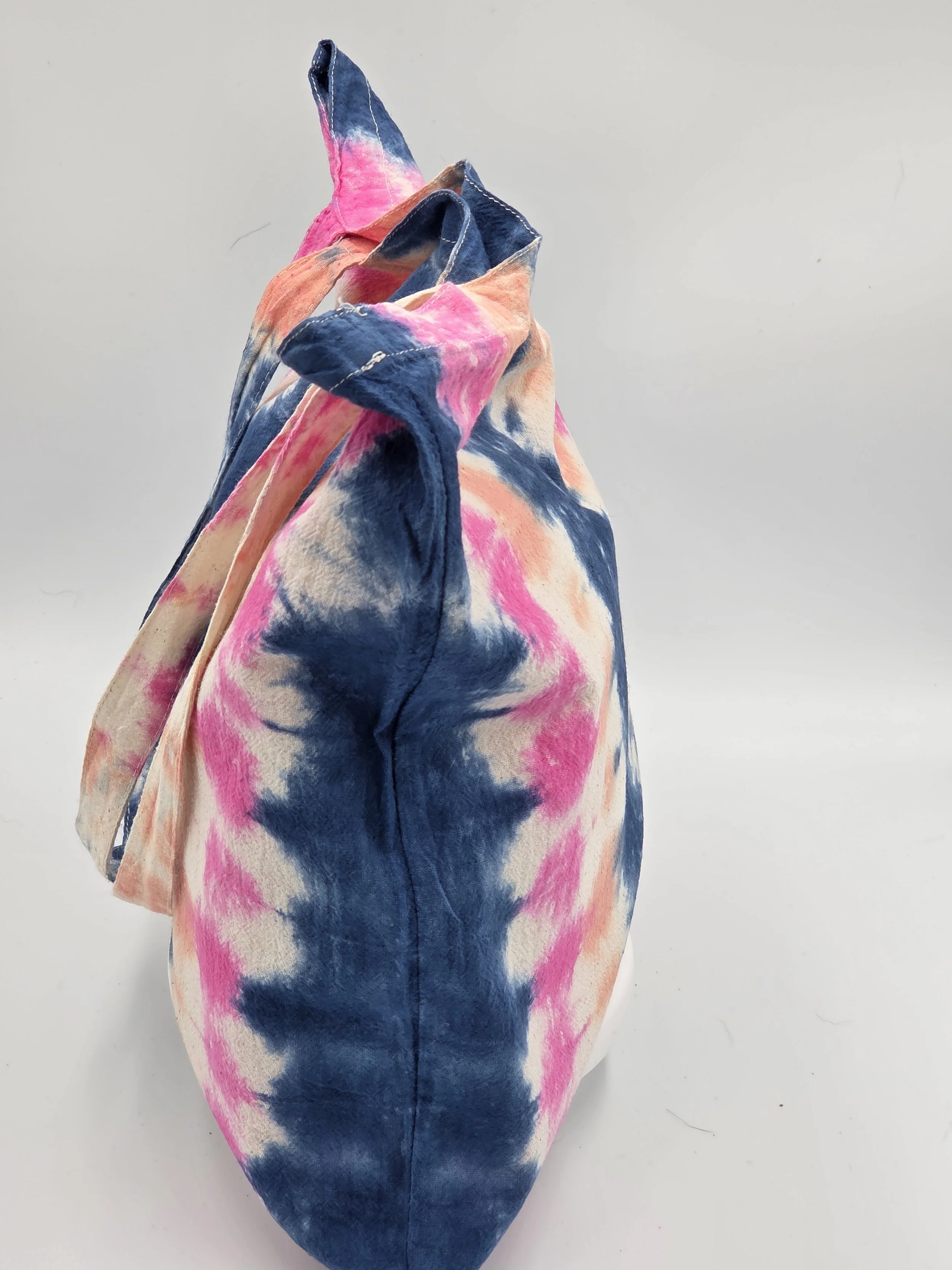 calico tote bag featuring vertical tie-dye columns of dark blue, soft pink, and pale orange with white spaces.