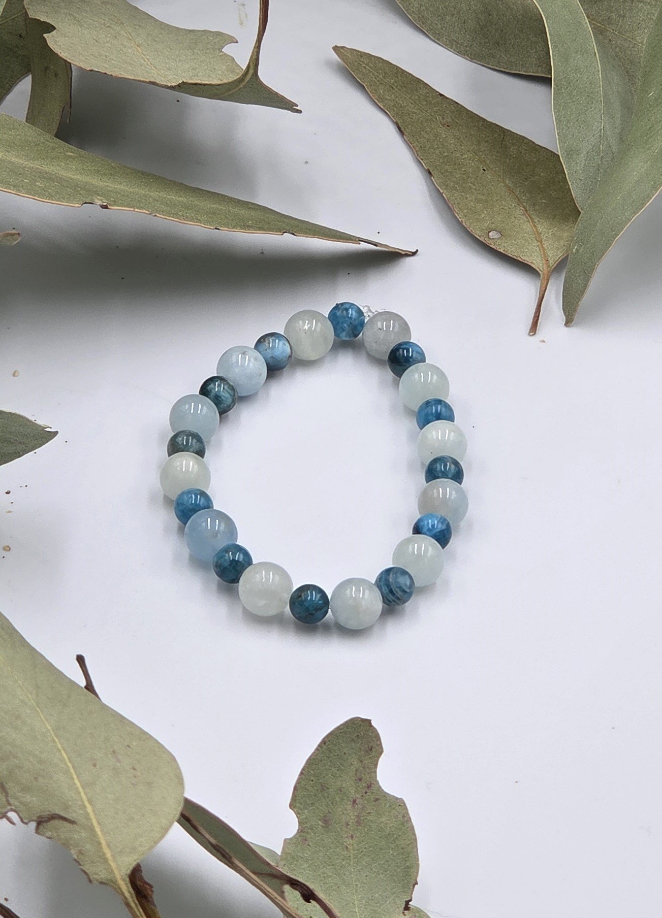 Alternating light blue-green Aquamarine beads and dark blue Apatite beads on an elastic gemstone bracelet.
