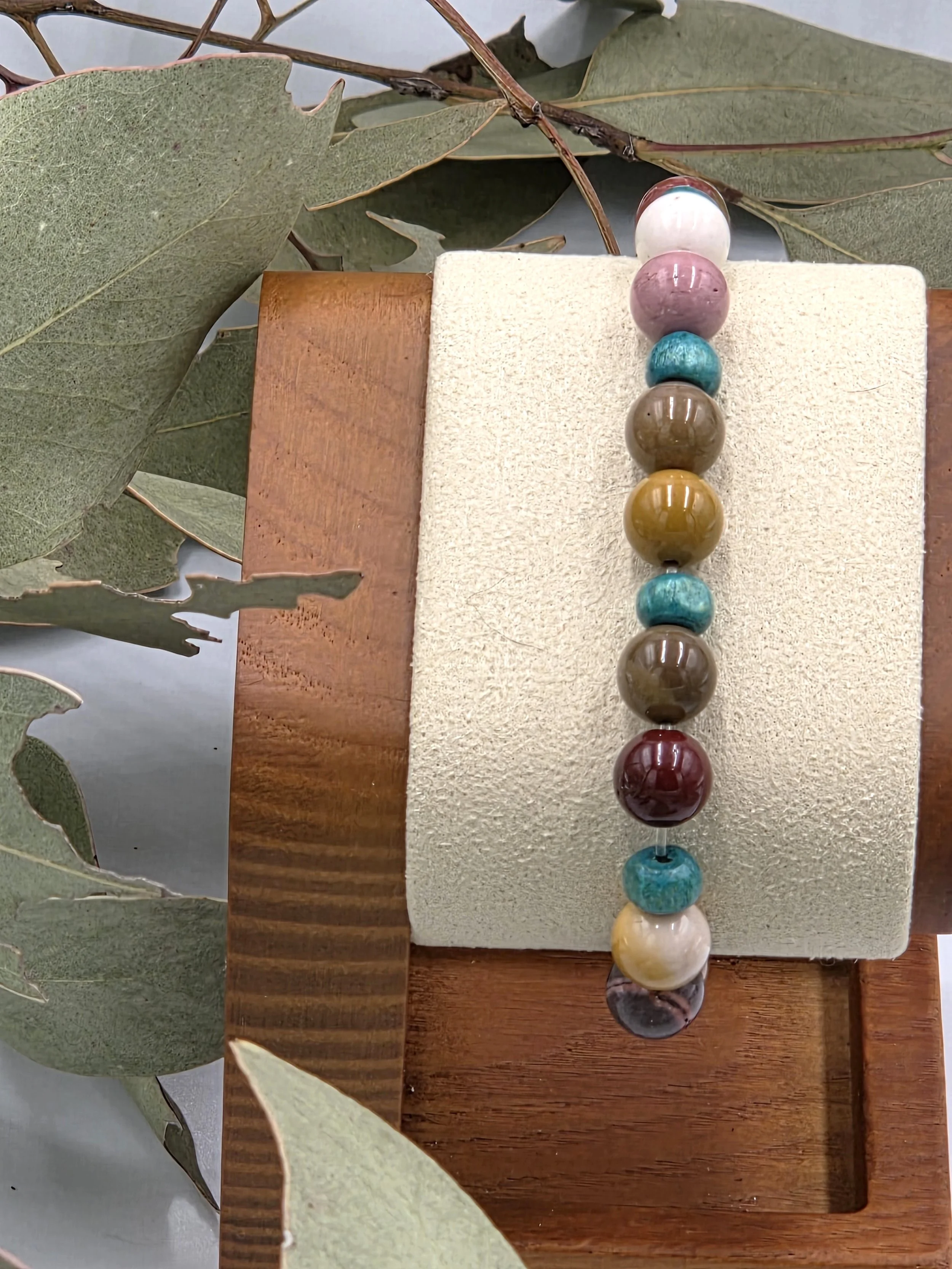 Earth-toned cream and brown Mookaite jasper beads alternating with small sky blue wood beads on an elastic bracelet.