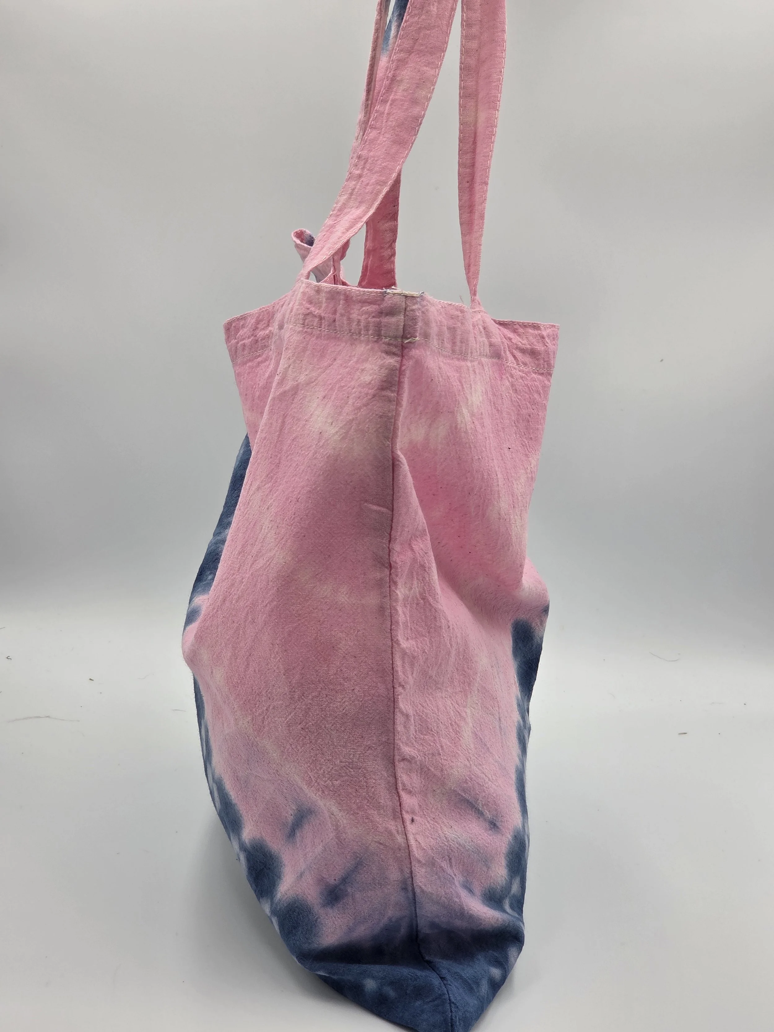calico tote bag with a diagonal tie-dye split featuring pink on top and dark blue on the bottom with three batik resist lines.