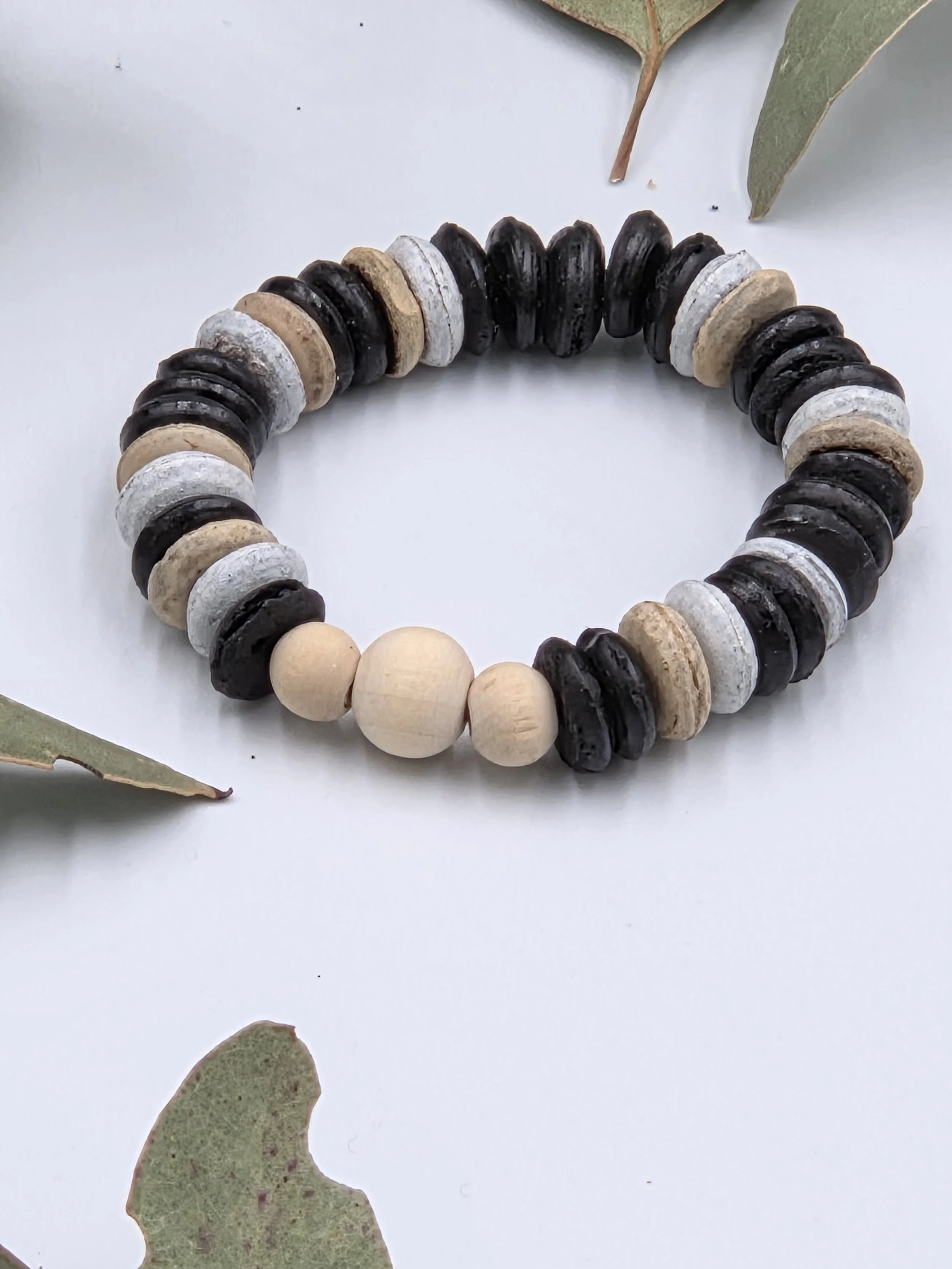 Striped brown and white coconut disc bracelet featuring a small trio of raw natural wood beads as a central focal point.