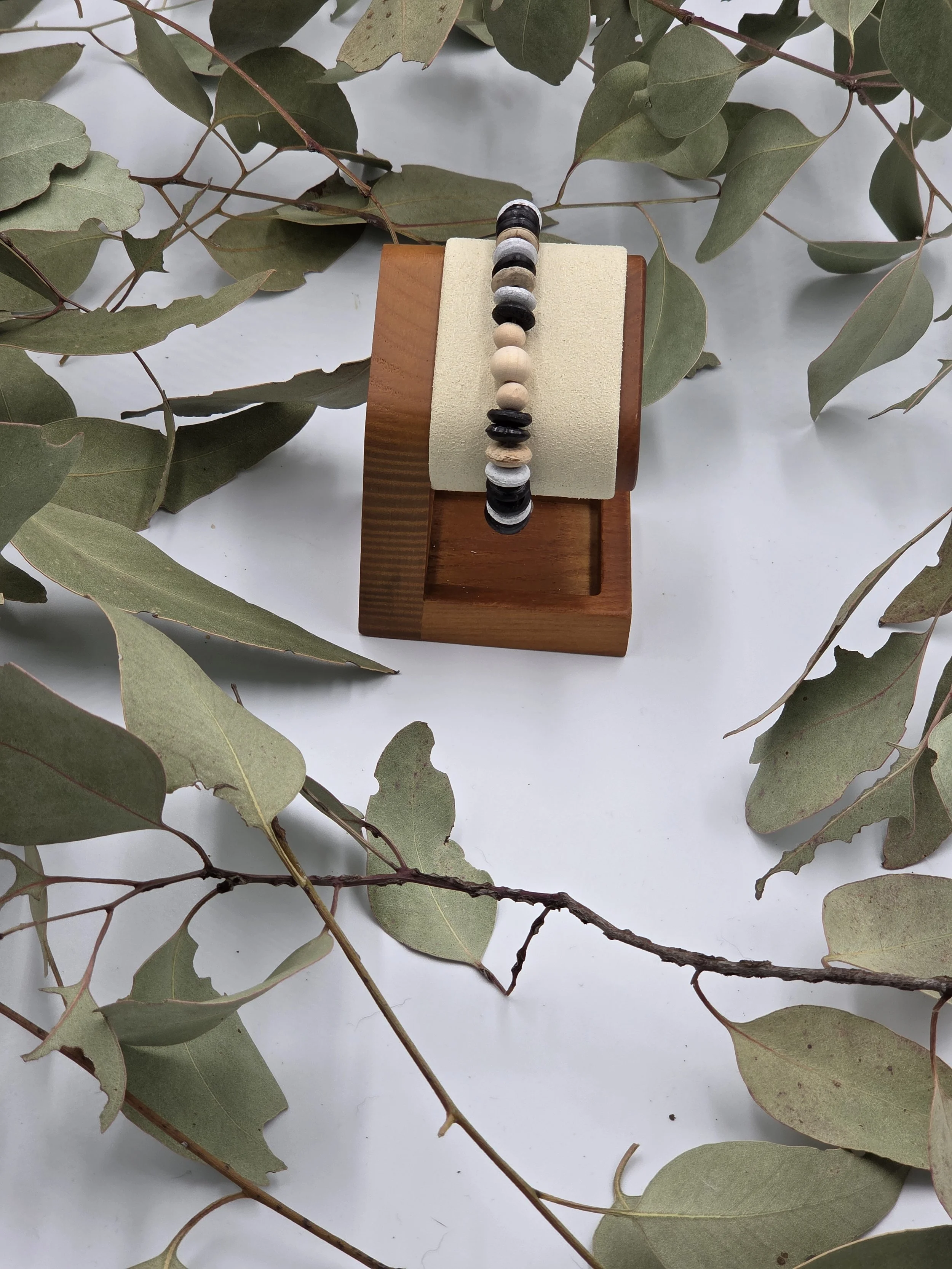Striped brown and white coconut disc bracelet featuring a small trio of raw natural wood beads as a central focal point.