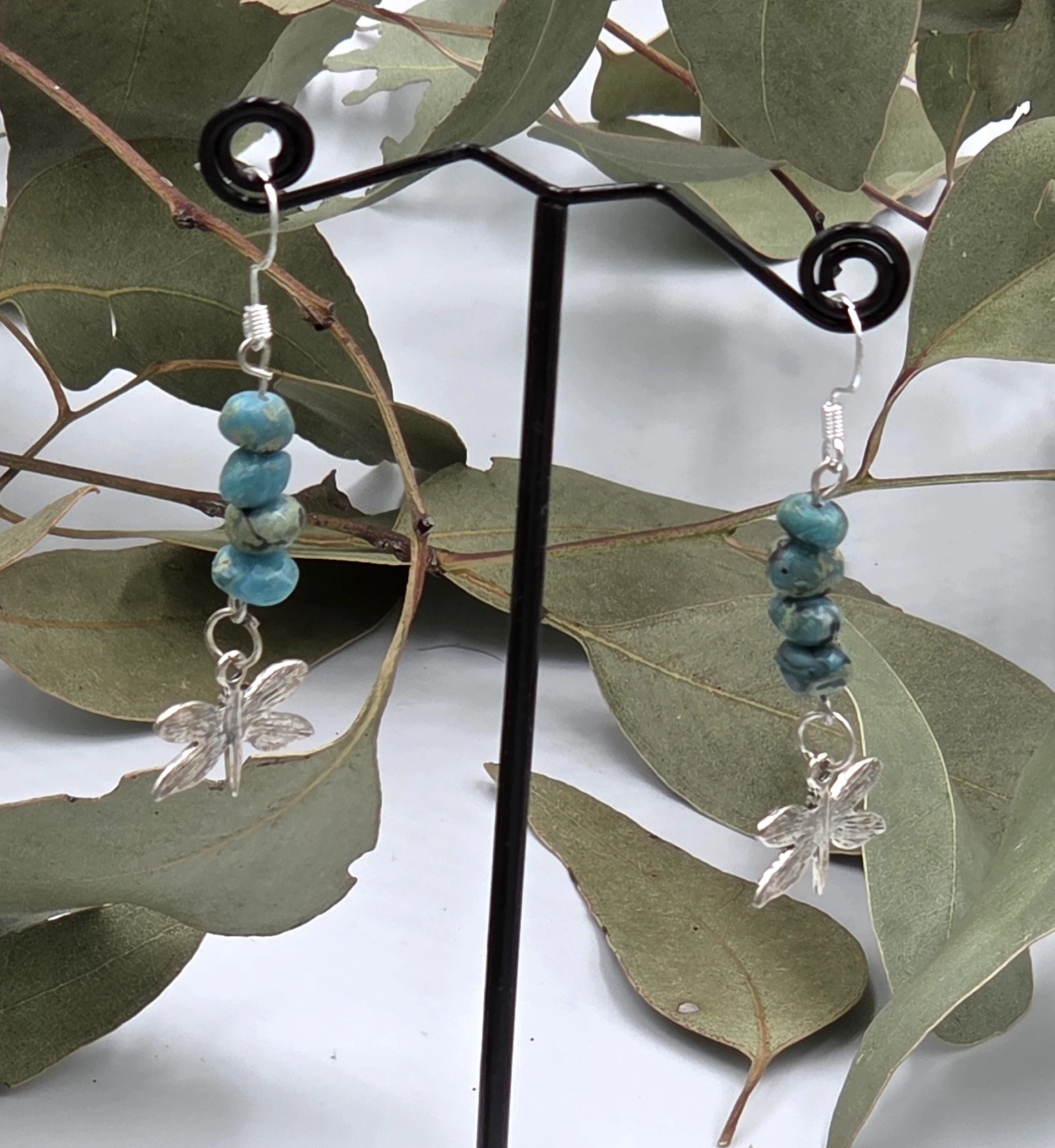 Dangle earrings with stacked turquoise nuggets and a silver dragonfly charm on sterling silver hooks.