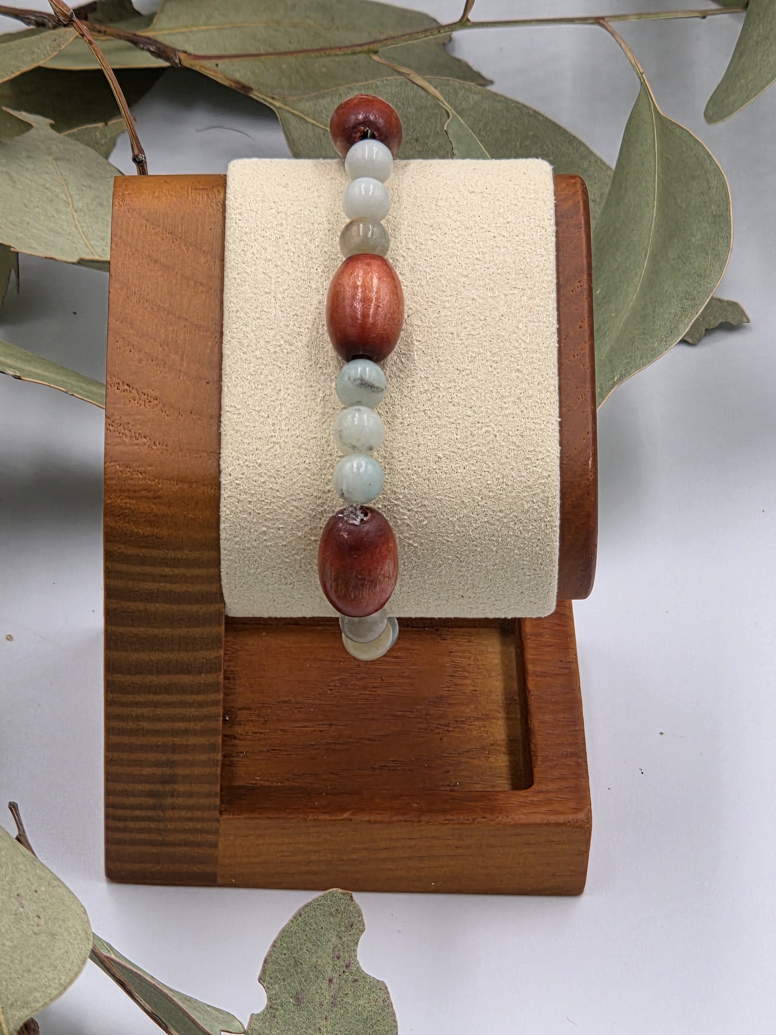 Smooth green Amazonite beads alternating in sets of three with single large brown oval wood beads on an elastic bracelet.