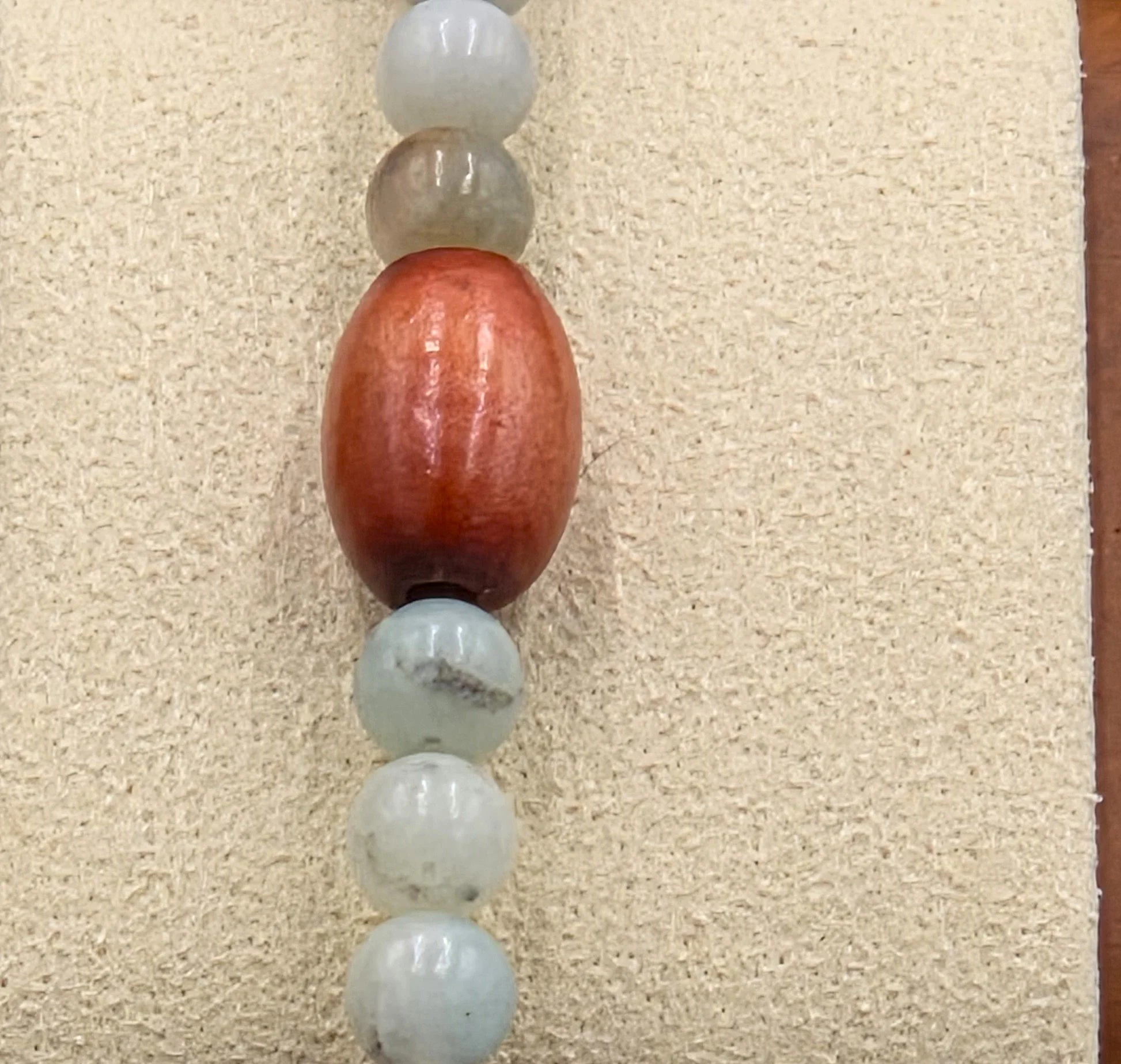 Smooth green Amazonite beads alternating in sets of three with single large brown oval wood beads on an elastic bracelet.