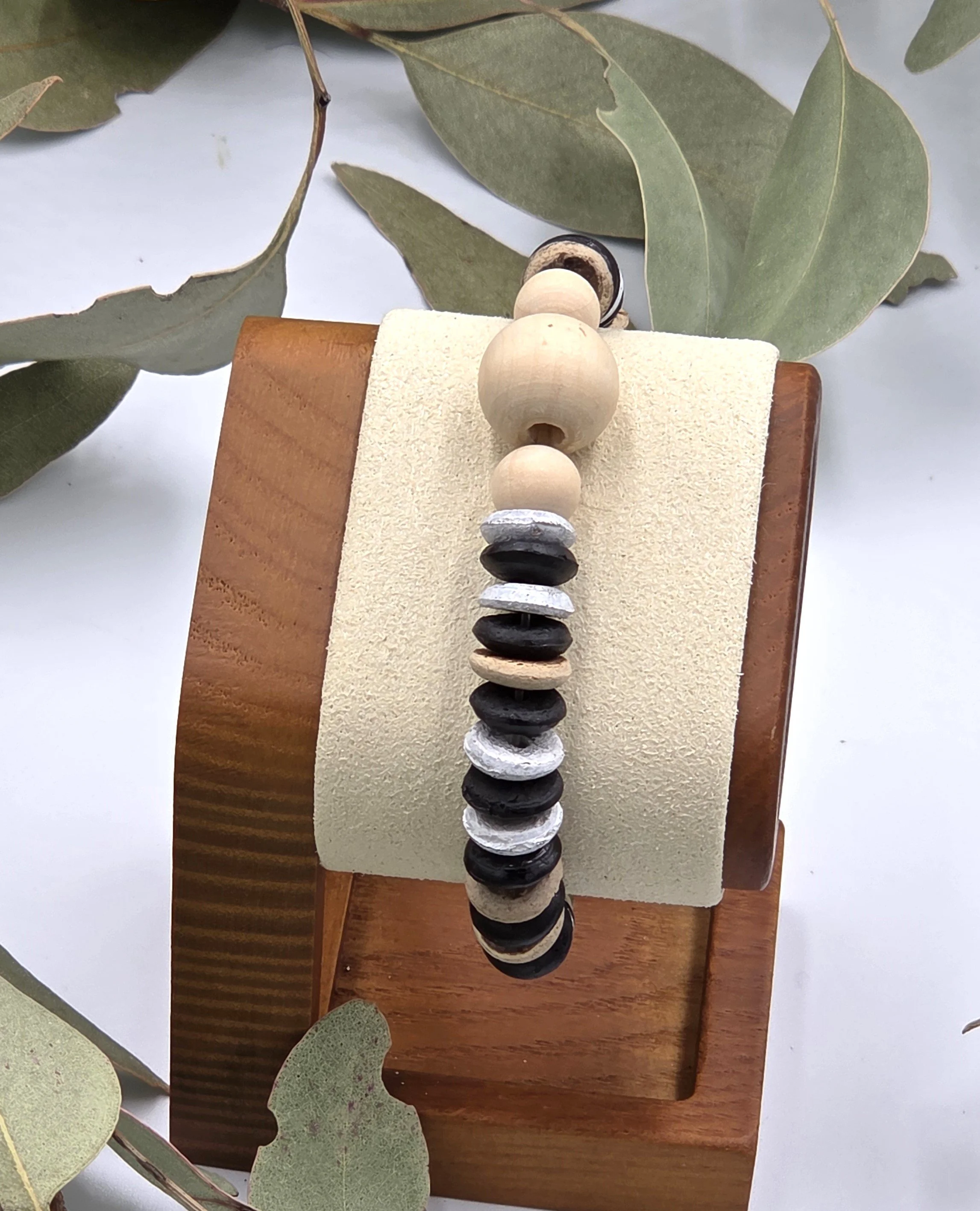 Striped brown and white coconut disc elastic bracelet featuring raw natural wood beads as a central focal point