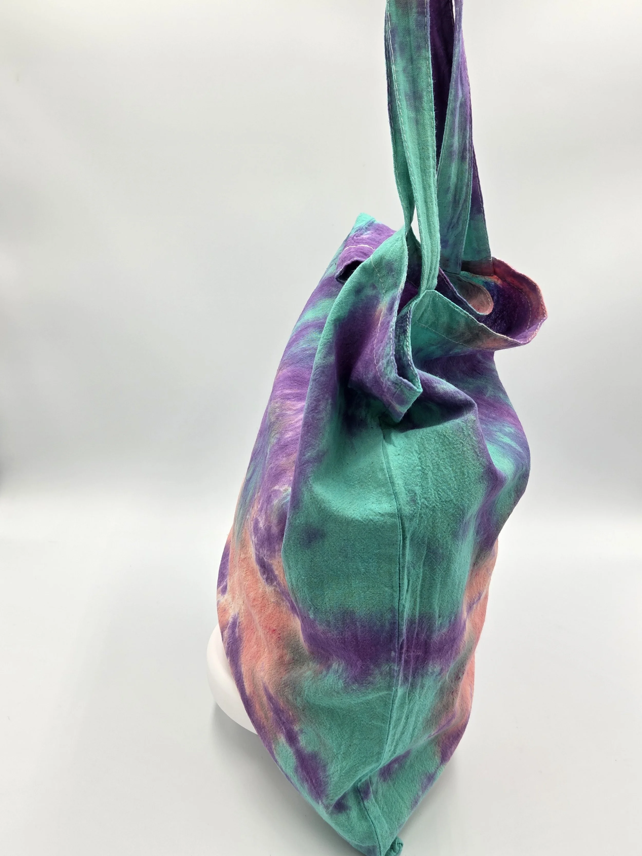 A calico tote bag featuring a tie-dye sea anemone pattern with a coral body and purple arms against a bright teal background.
