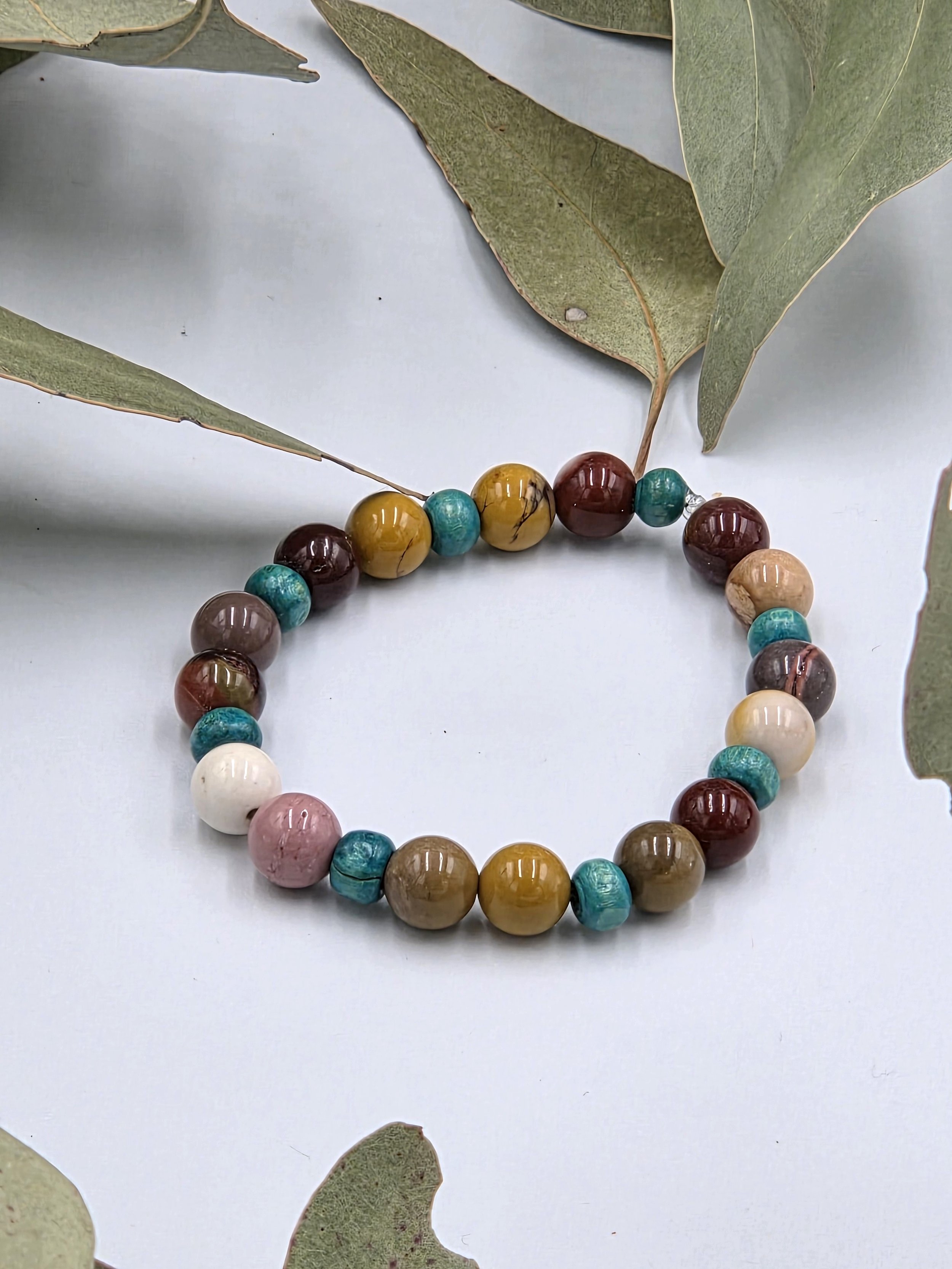 Earth-toned cream and brown Mookaite jasper beads alternating with small sky blue wood beads on an elastic bracelet.
