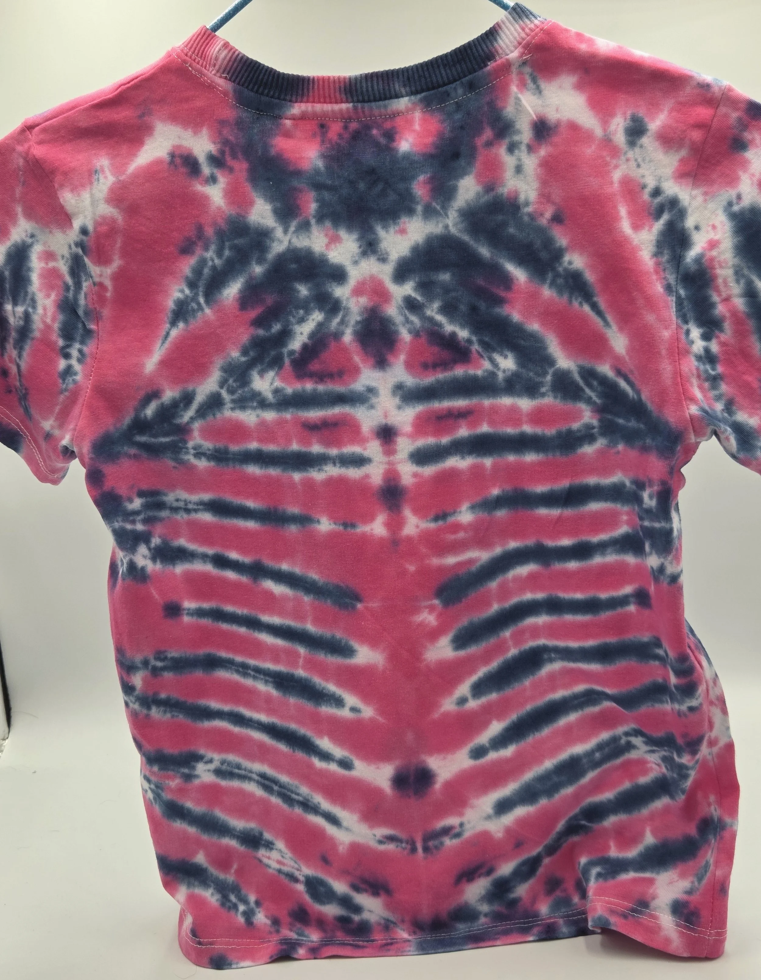 child size 7 cotton t-shirt featuring a fuchsia rib and spine tie-dye pattern against a dark blue background.