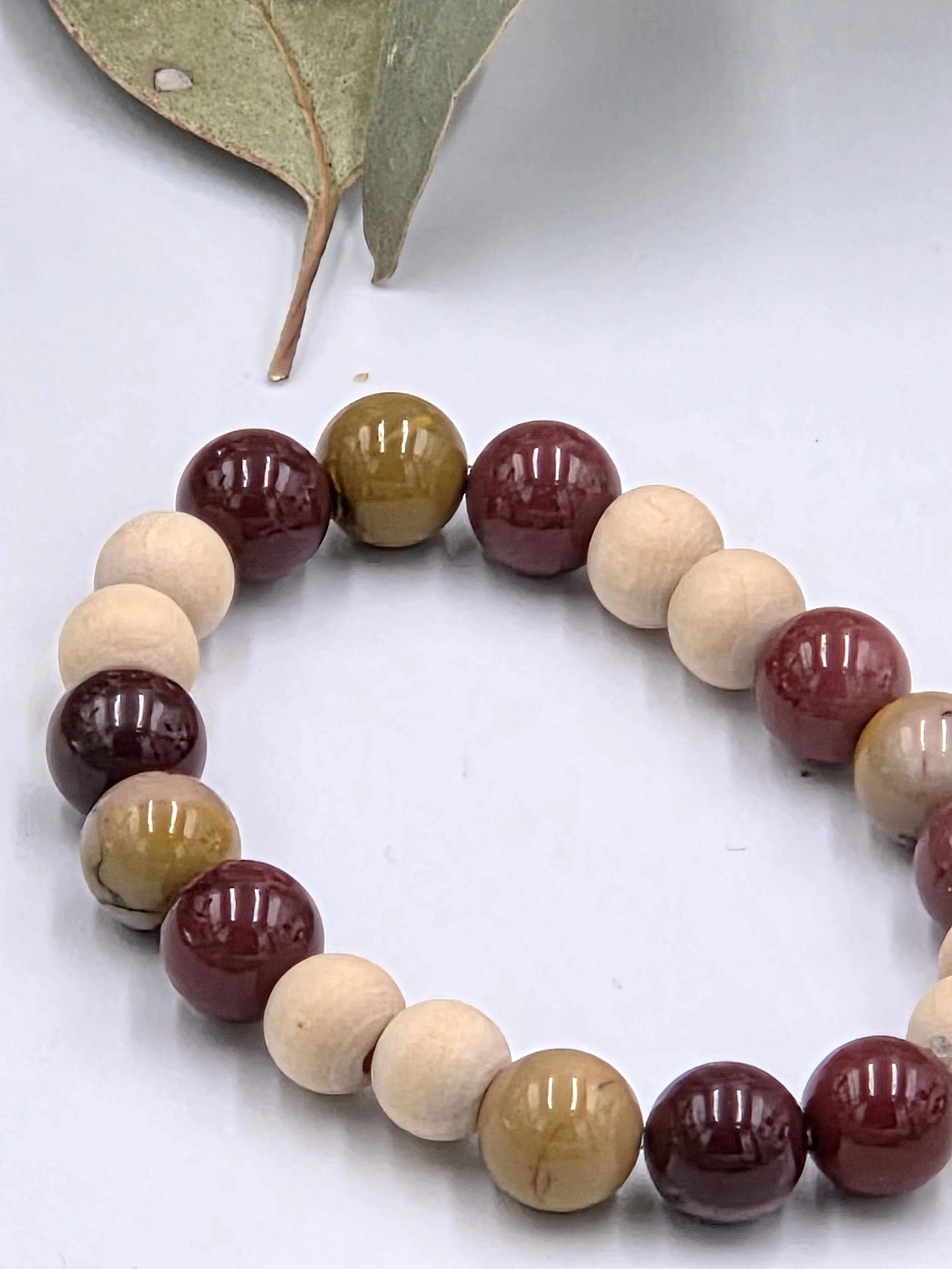 Earthy red and yellow Mookaite jasper beads alternating with small natural wood beads on an elastic bracelet.