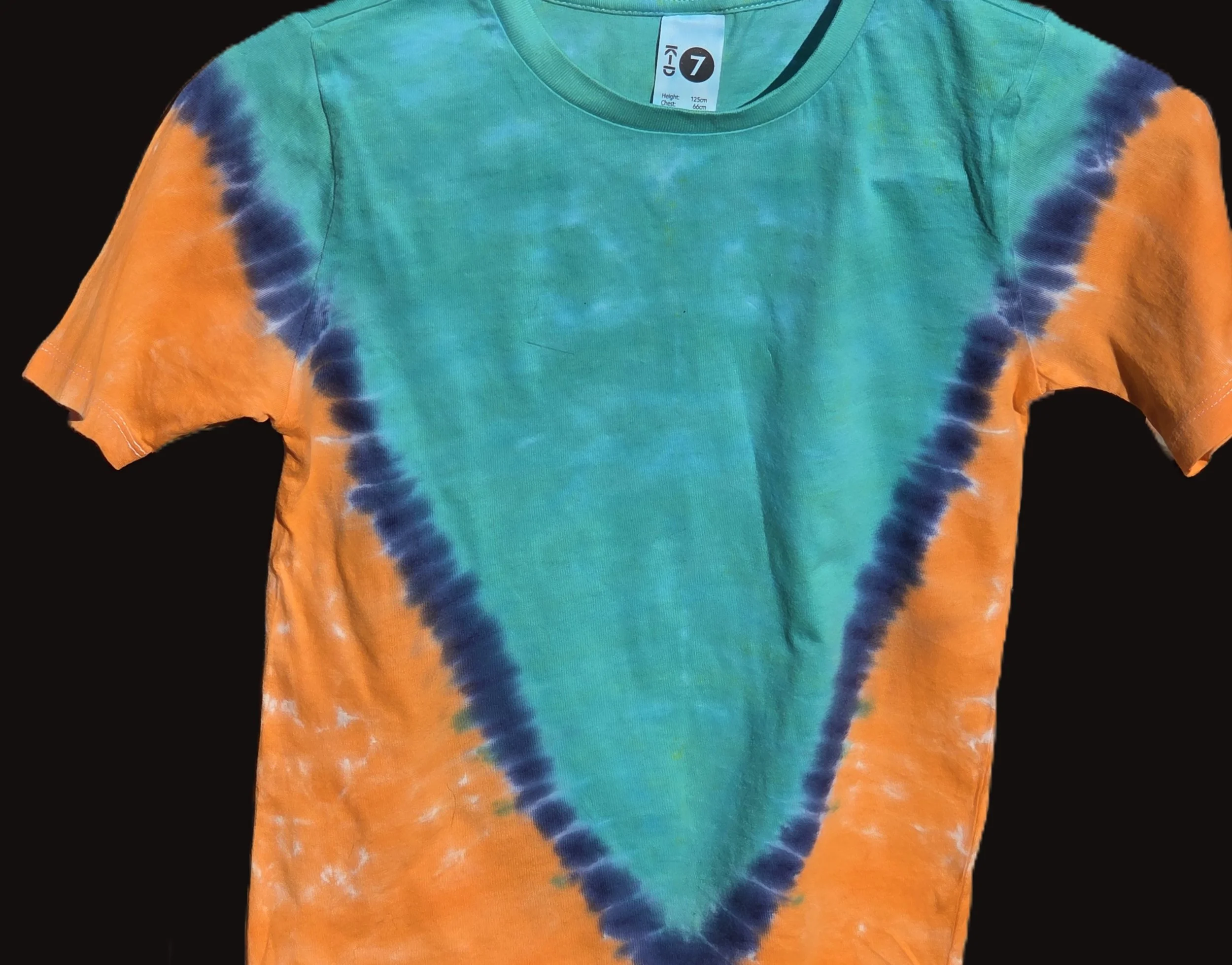 A child size 7 cotton t-shirt featuring a large teal and dark blue V-shape tie-dye pattern against a bright orange background.