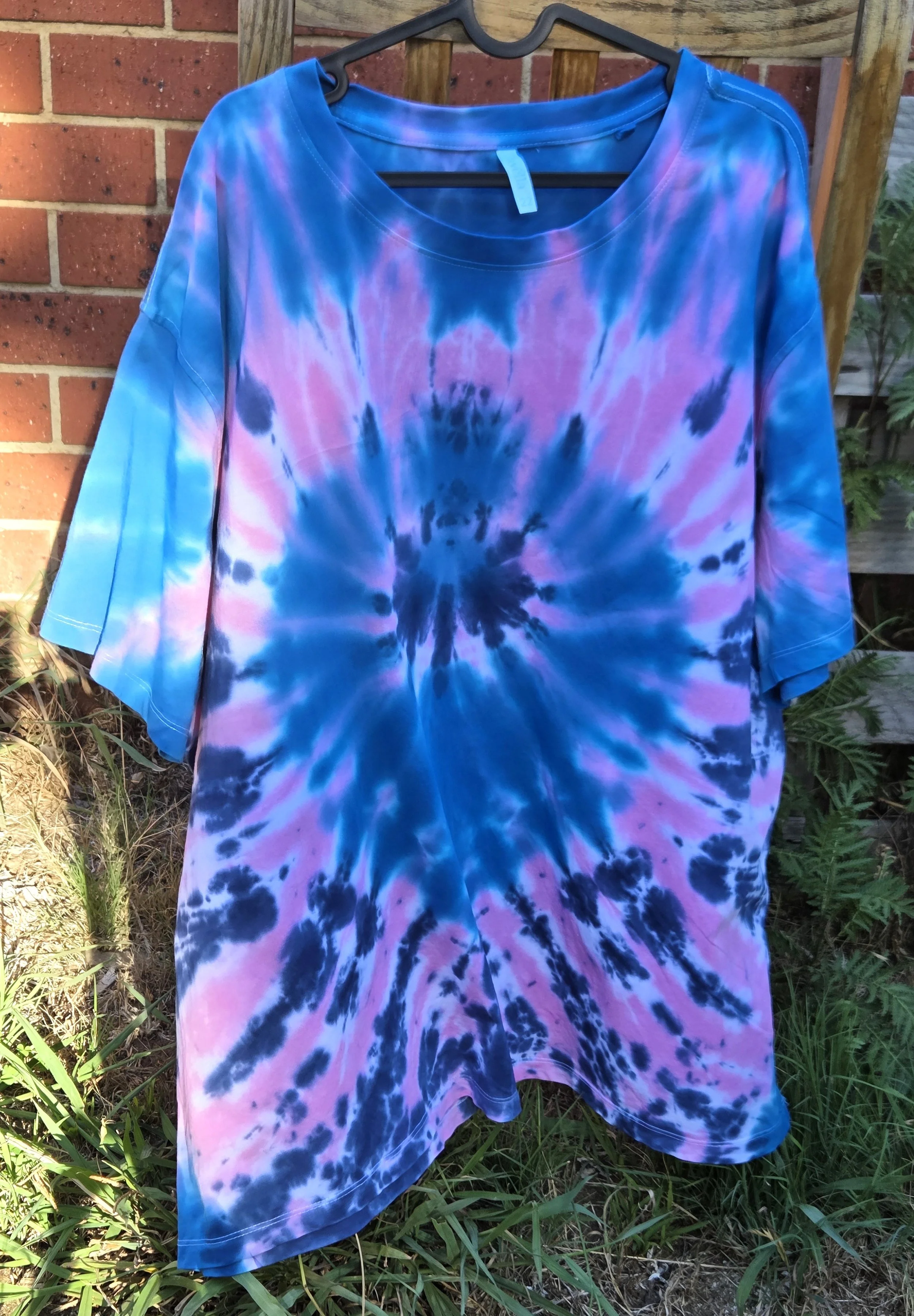 Women's size 22 hand-dyed cotton T-shirt with a blue and pink twist pattern resembling a large flower bloom. OOAK wearable art by Livity Studio."