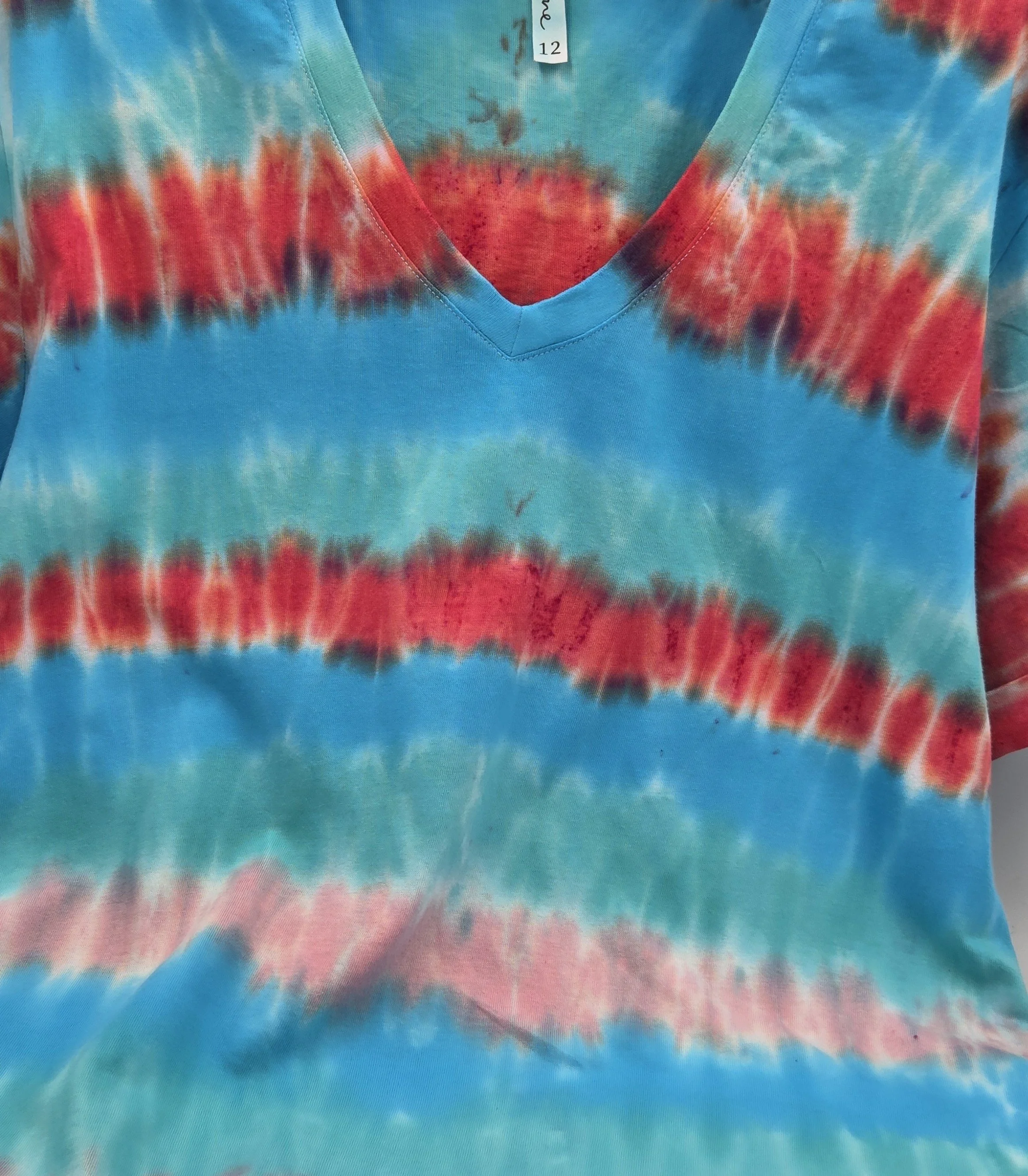 An adult size 12 women's V-neck cotton t-shirt with horizontal tie-dye stripes in coral, pink, turquoise, and Aegean green