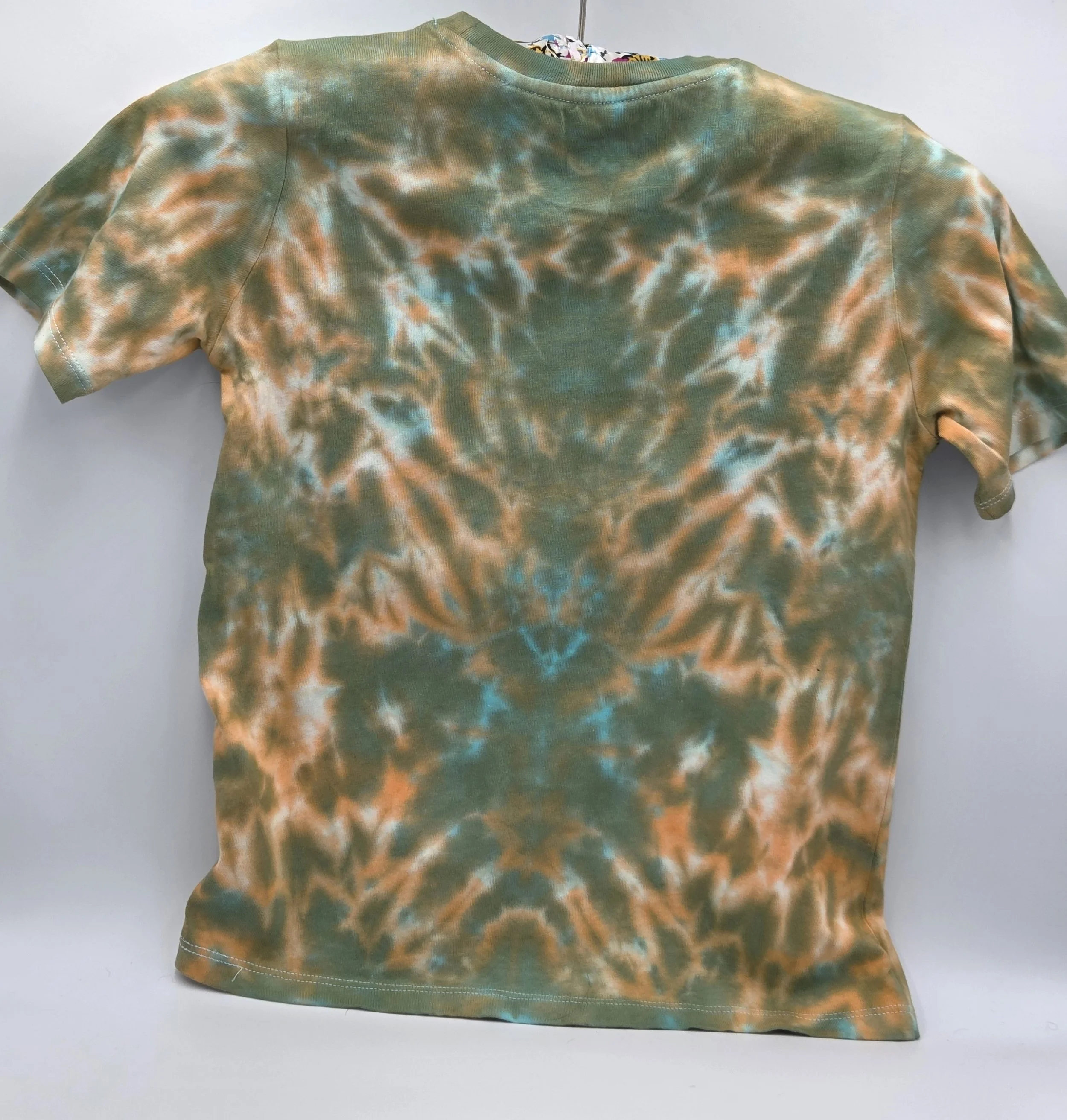 back view of A child's size 6 t-shirt featuring a soft, pastel tie-dye tiger stripe pattern of khaki and orange with hints of sky blue.
