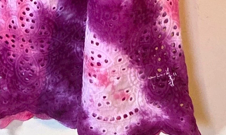 showing repair of A woman's large white lace bohemian top with bell sleeves, featuring a vivid hand-dyed fuchsia and pink spider flower pattern..jpg