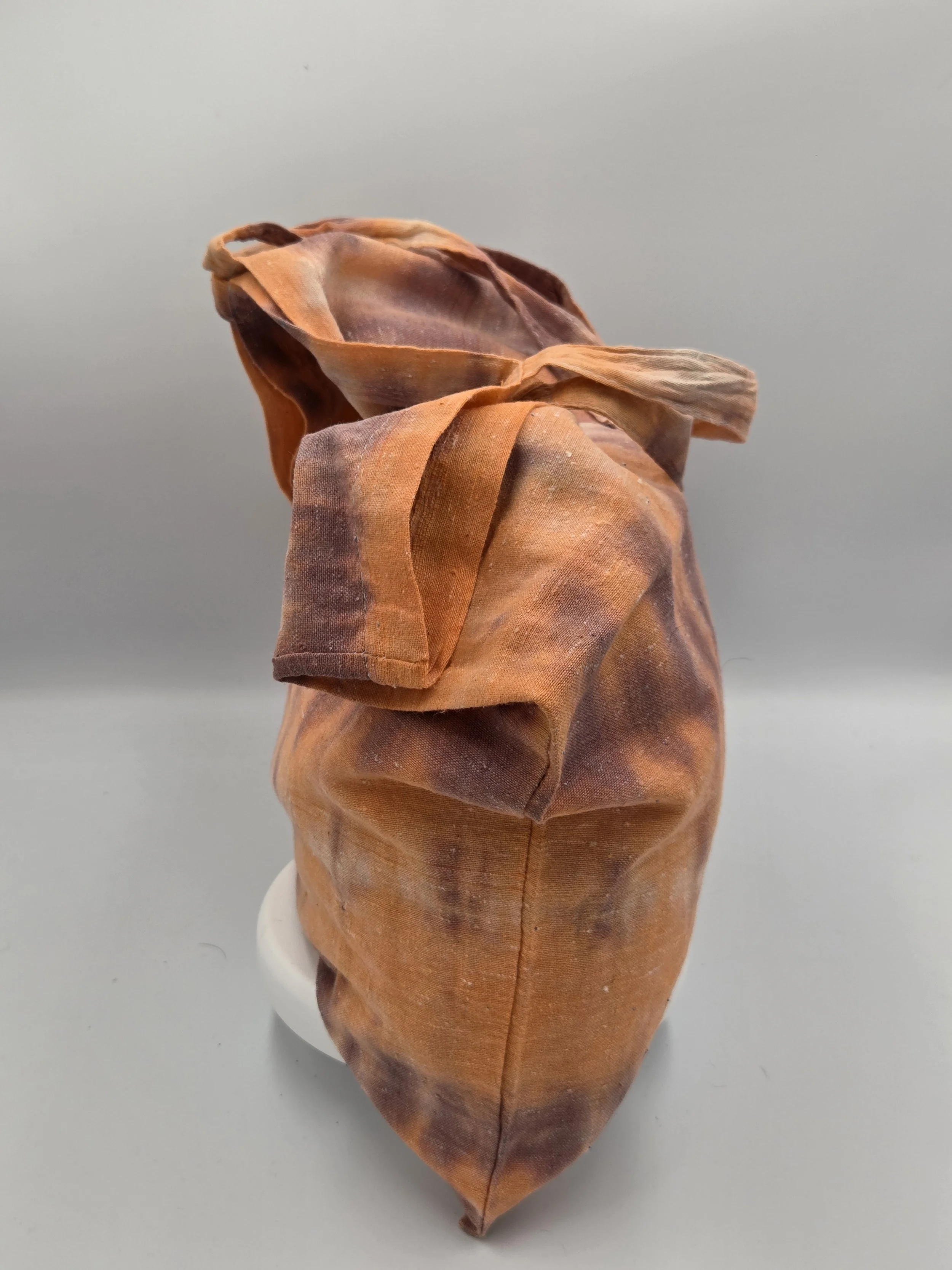 Hand-dyed calico cotton tote bag with a faded horizontal rainfall pattern in light brown and pastel orange. OOAK textile art by Livity Studio.