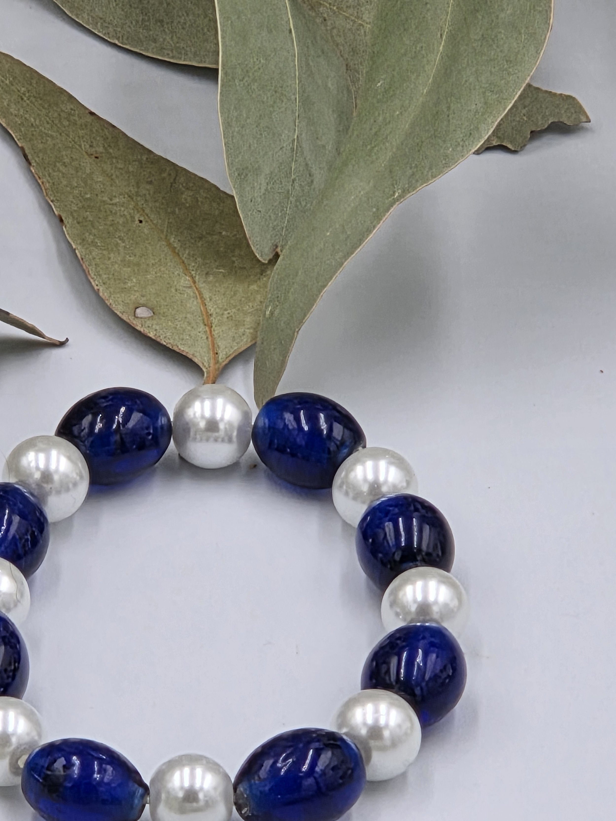 Glossy dark blue oval glass beads alternating with luminous white glass pearls on an elegant elastic bracelet.