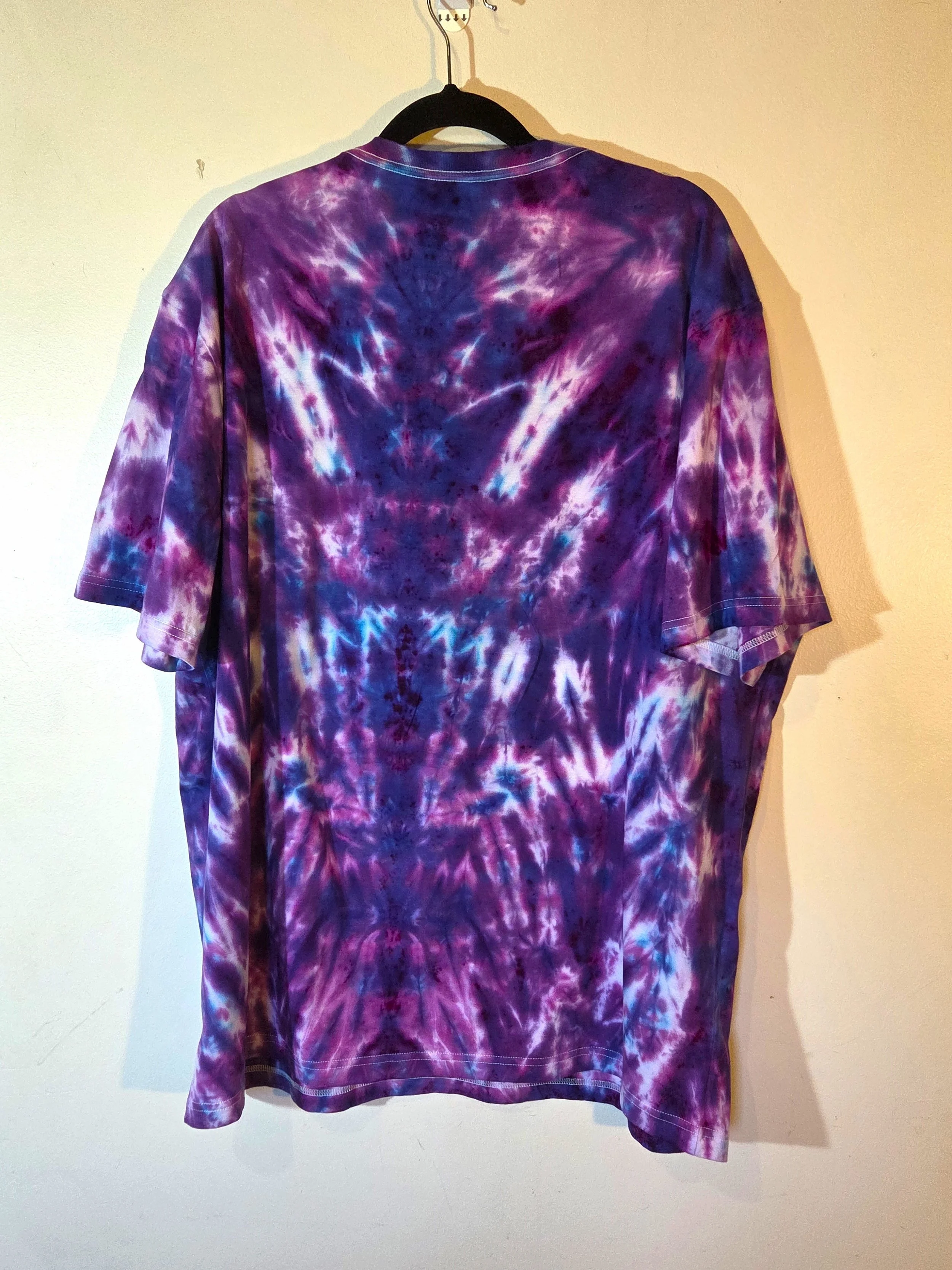 An adult XXL t-shirt featuring an intense red and burgundy tie-dye pattern that shapes a narrow fan at the neck and expands into a horizontal psychedelic design near the hem.