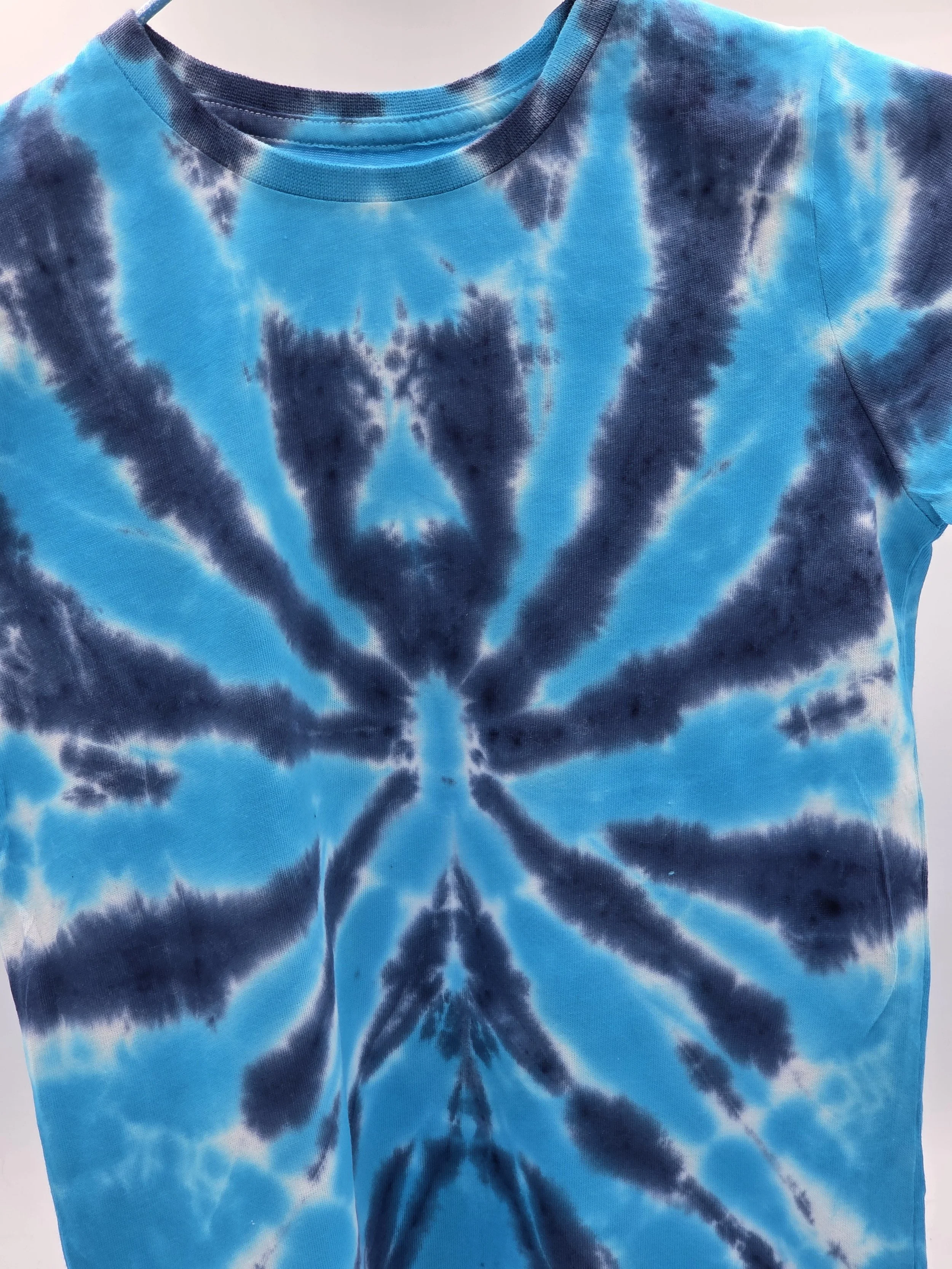 child size 3 cotton t-shirt featuring a dark blue tie-dye spider pattern against a bright turquoise background.